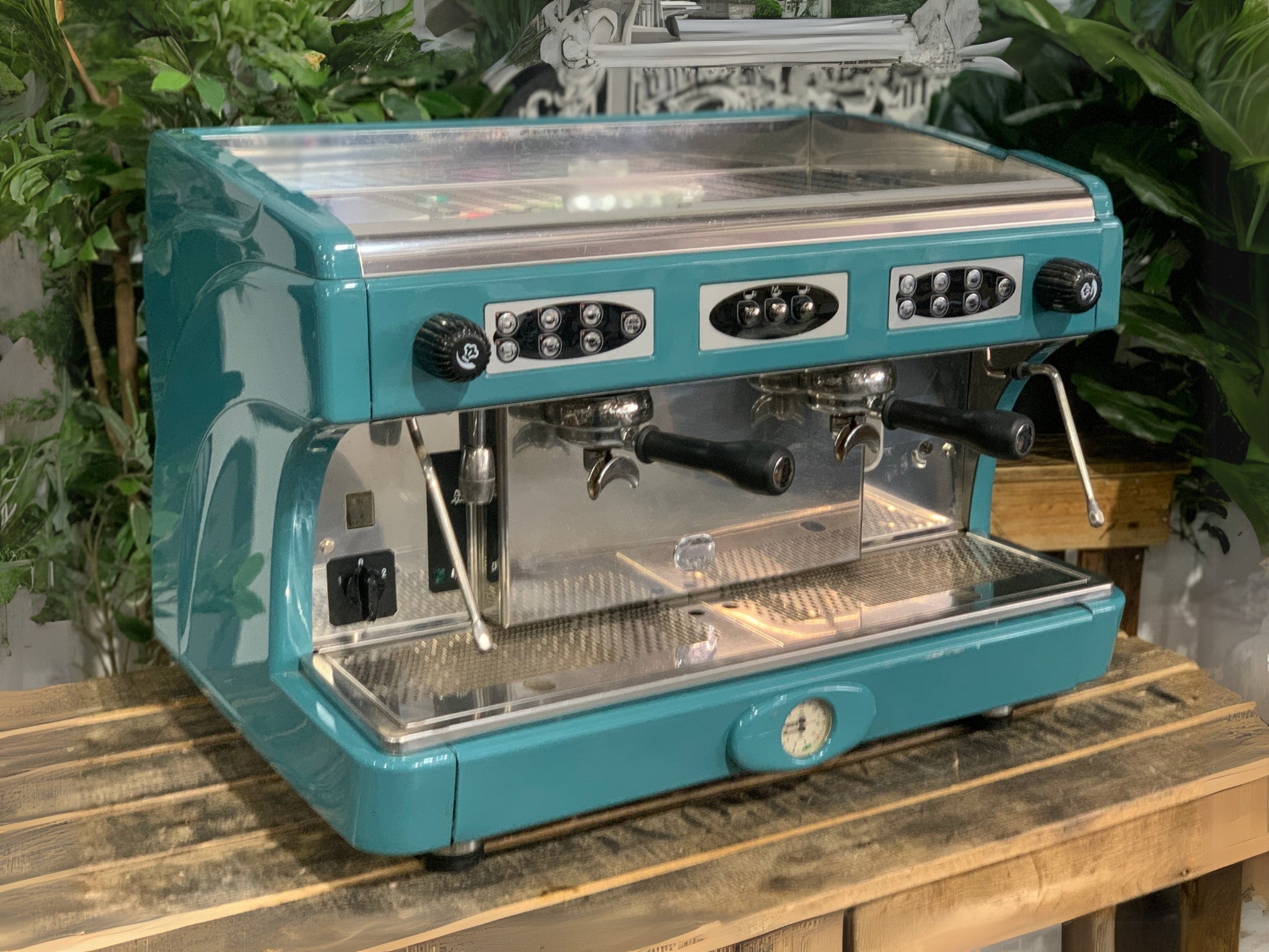 Astoria Calypso 2 Group Aqua Espresso Coffee Machine sitting on a wooden bench. Machine on angle front and side visible.