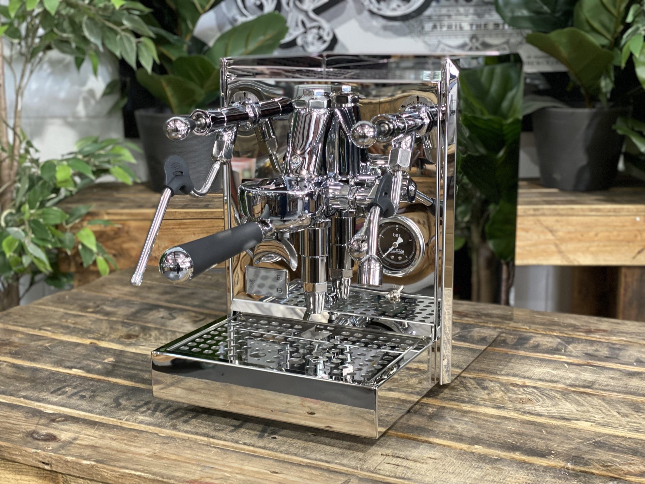 Bellezza Gulia Lever 1 Group Stainless Espresso Machine - New displayed on a wooden table with green plants in the background.