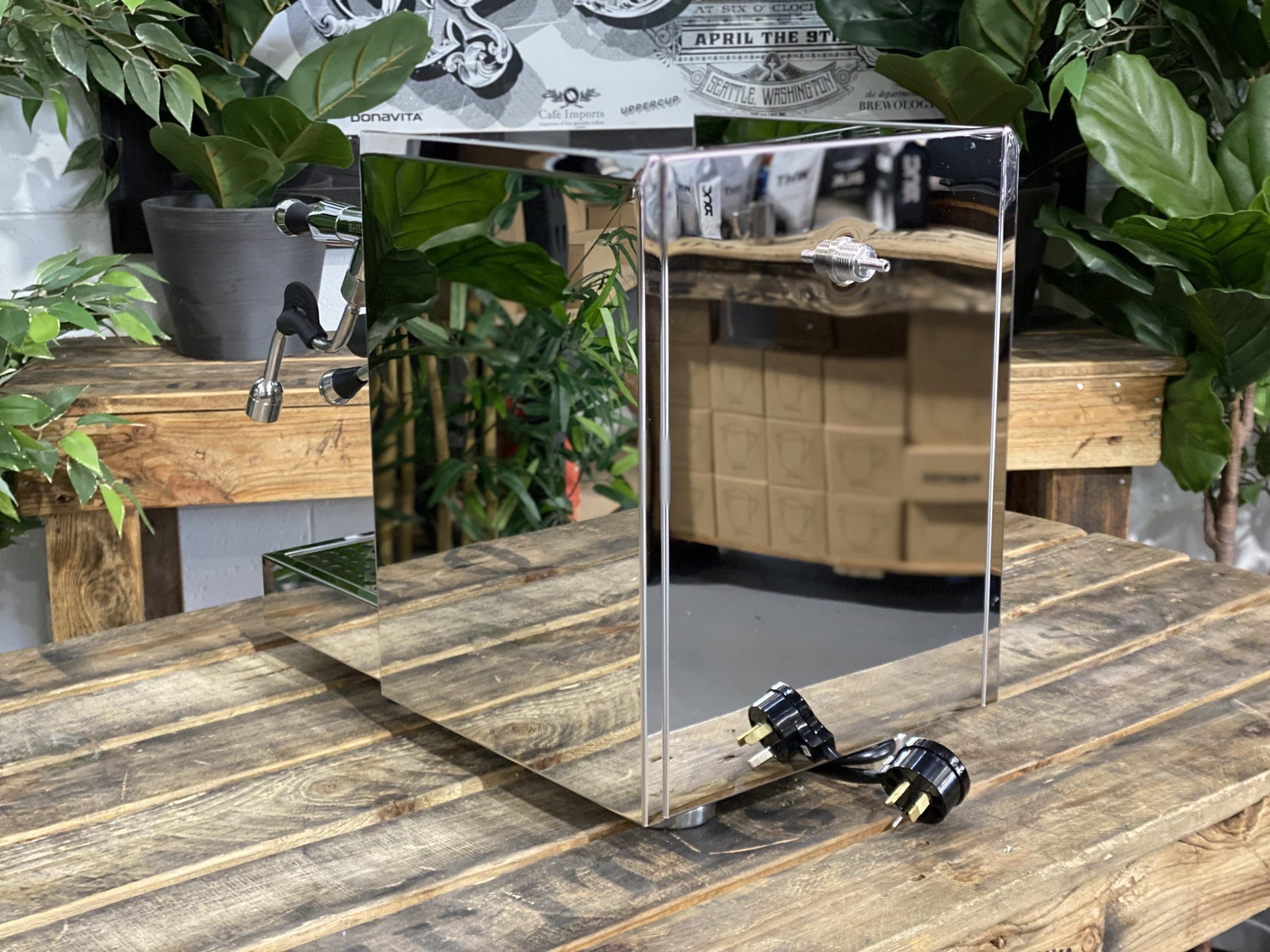 Bellezza Gulia Lever 1 Group Stainless Espresso Machine - New displayed on a wooden table with greenery in the background.