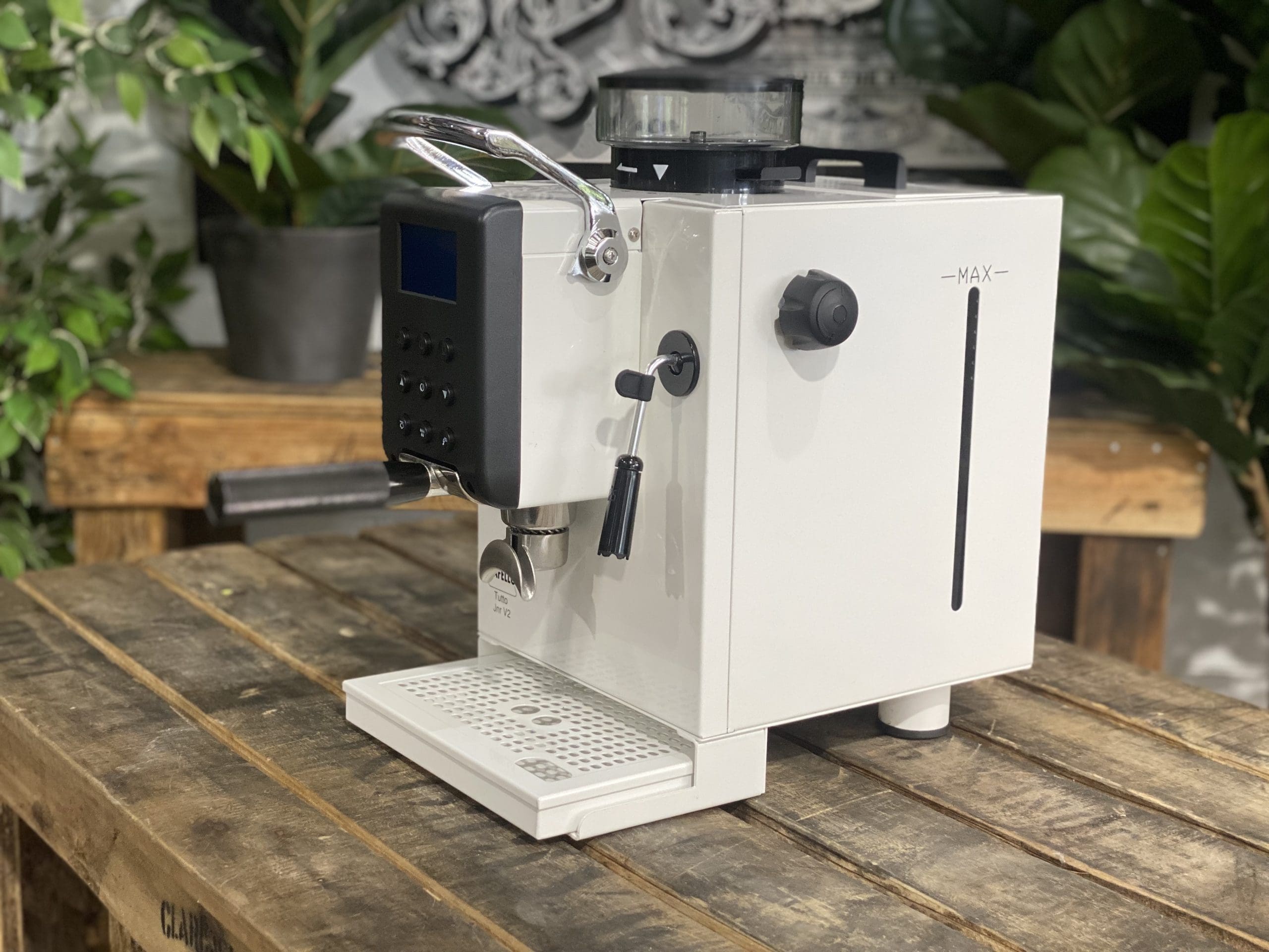 Cafello Tutto Junior V2 Espresso Machine White - New displayed on a wooden table with plants in the background.