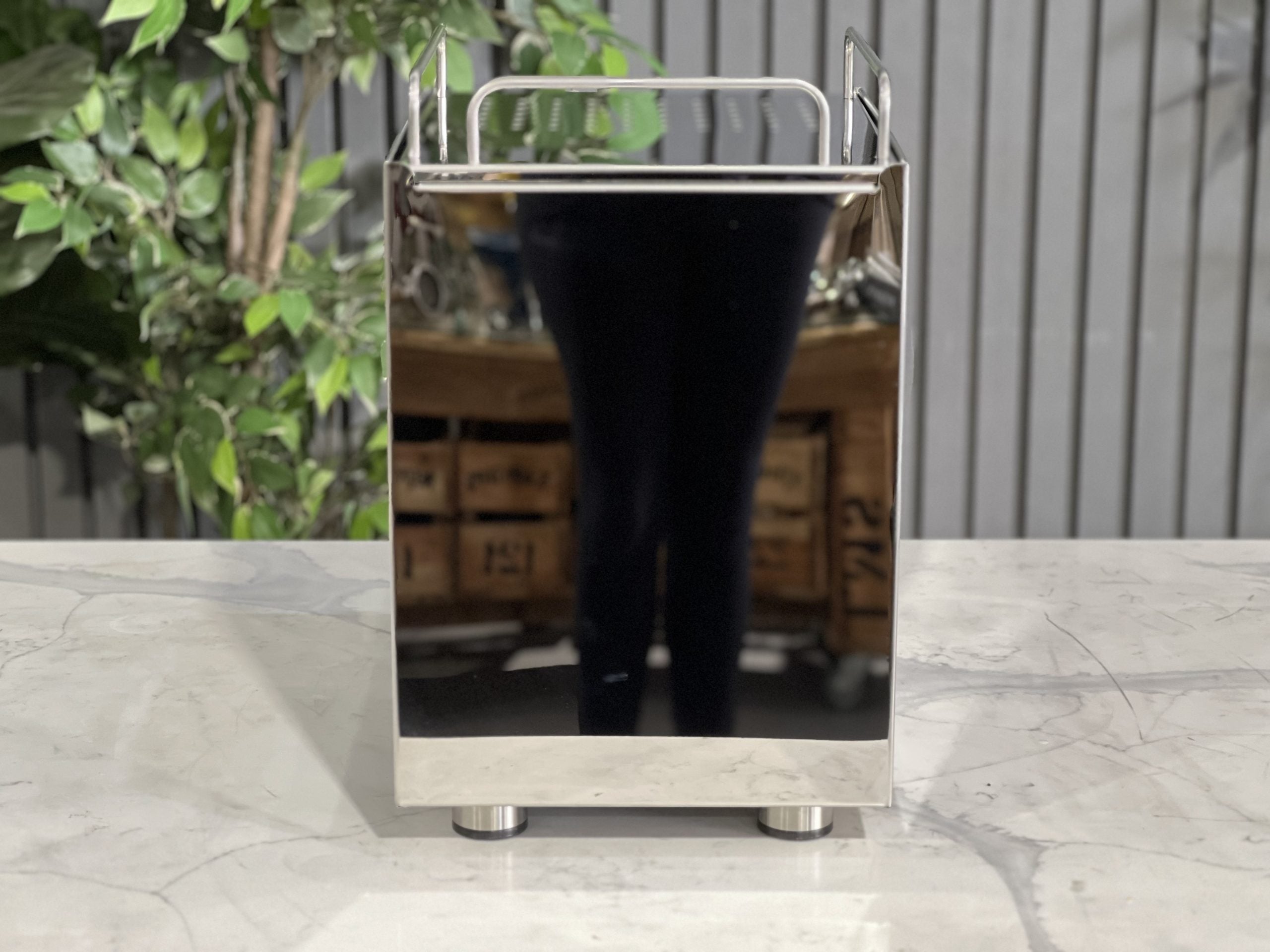ECM Classika PID 1 Group Coffee Machine Stainless - New espresso coffee machine, rear view displaying the water tank access, compact stainless steel body, and connections, placed on a marble bench with leafy greenery behind.