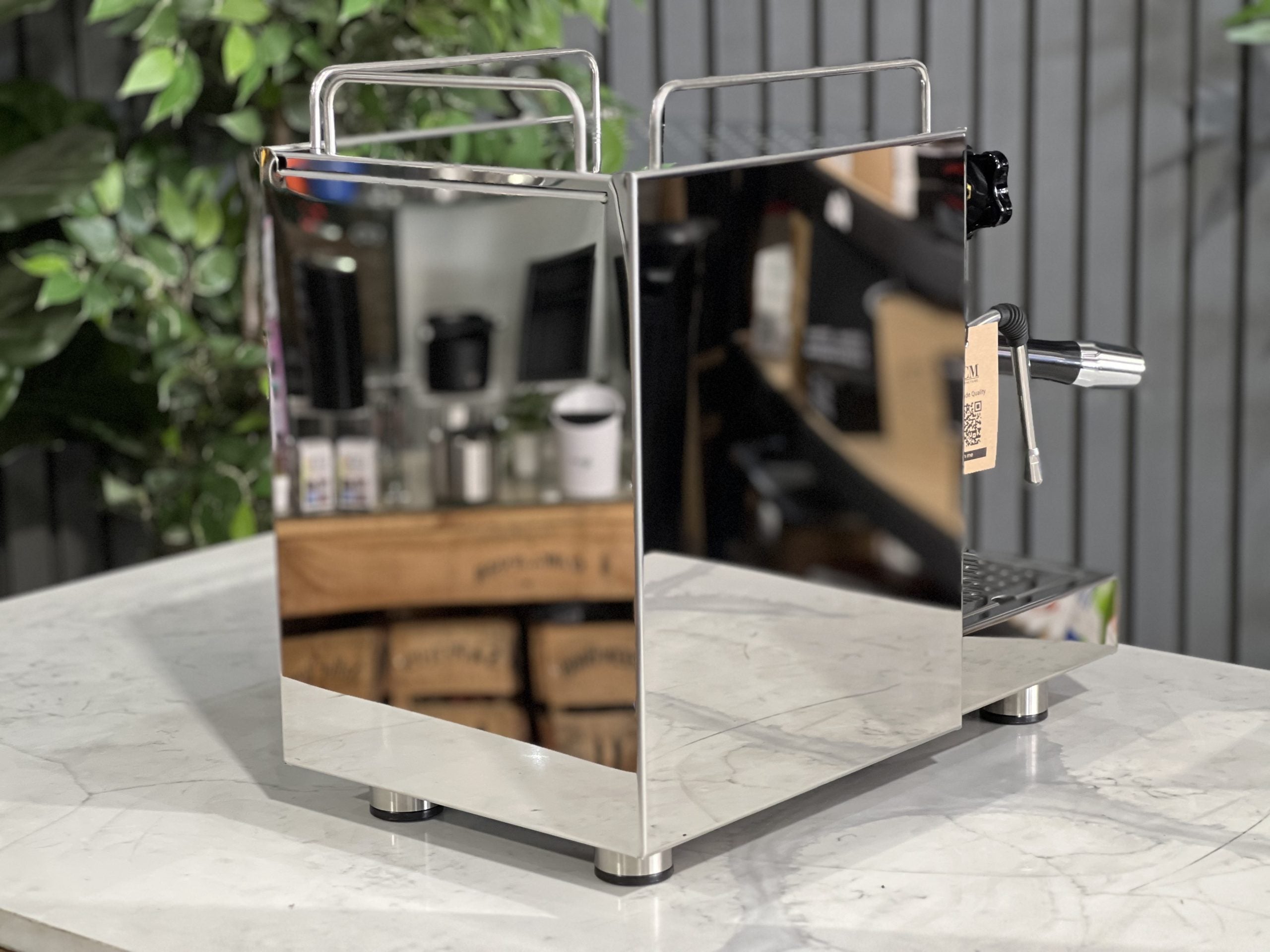 ECM Classika PID 1 Group Coffee Machine Stainless - New espresso coffee machine, angled rear view showing the water tank and overall compact design, positioned on a white marble bench with greenery in the background.