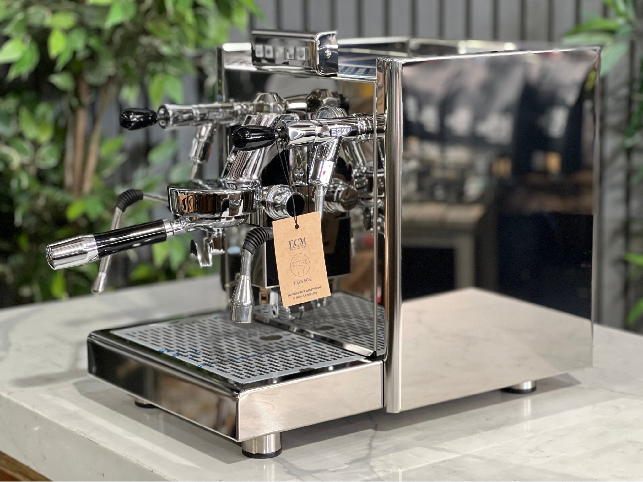 ECM Elektronika II Profi Rotary 1 Group Coffee Machine Stainless – New, angled view showing stainless steel body, E61 group head, steam wand, and cup warmer on a marble bench with greenery behind, perfect for a home espresso setup.