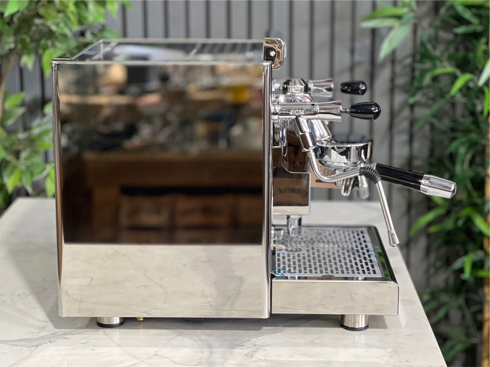 ECM Elektronika II Profi Rotary 1 Group Coffee Machine Stainless – New, side view displaying stainless steel finish, steam wand, and high cup clearance on a marble bench with greenery behind.