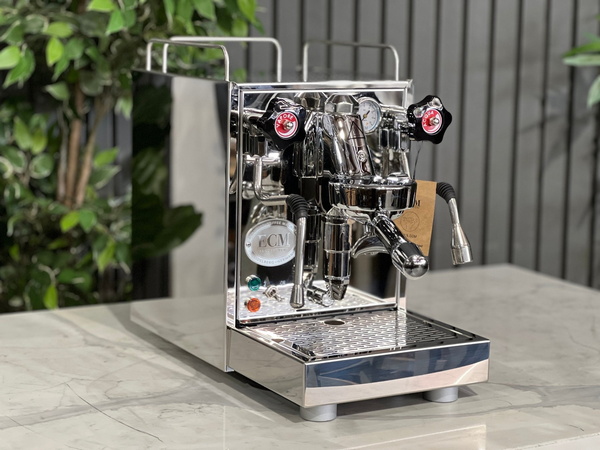 ECM Mechanika VI Slim 1 Group Coffee Machine Stainless on a counter with lush greenery background.