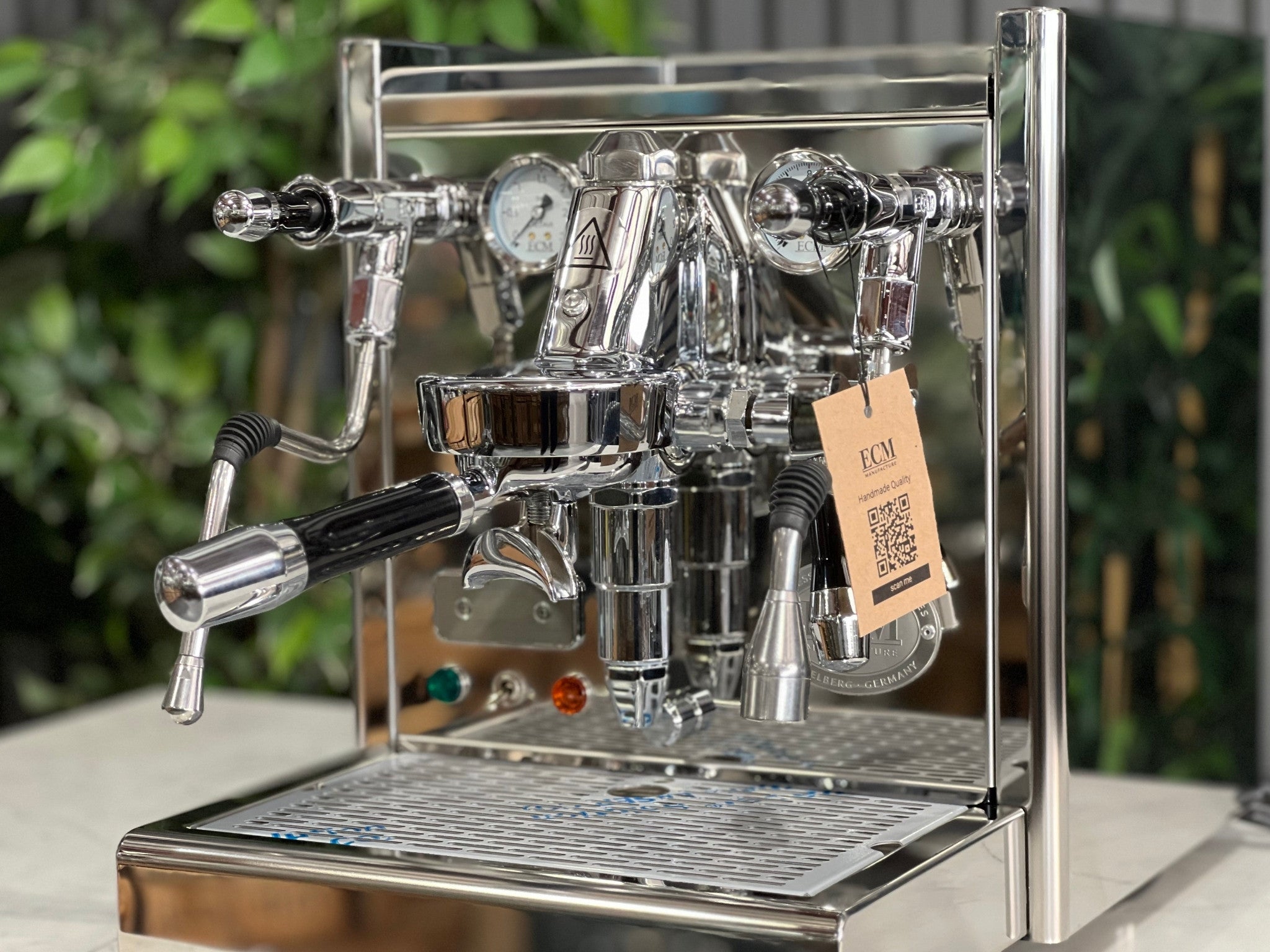 Close-up of the ECM Technika V Profi Rotary PID 1 Group Coffee Machine Stainless – New espresso coffee machine front view, showing the E61 group head, pressure gauges, and steam levers in detail on a marble bench with greenery behind.