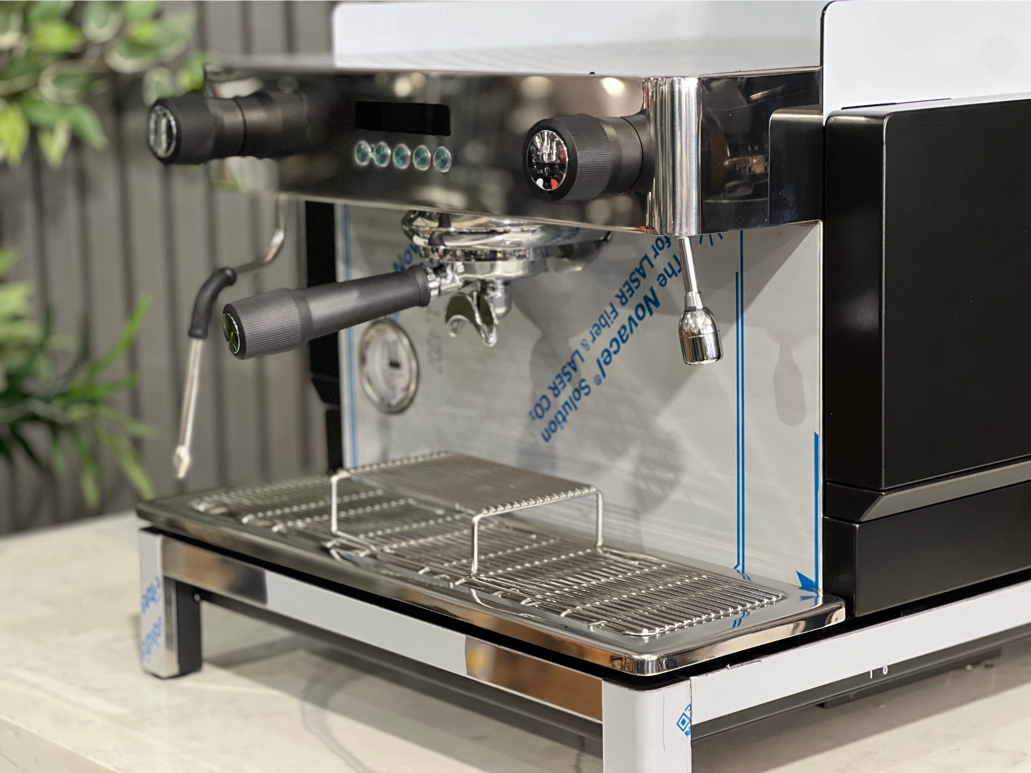 Expobar Crem EX3 Compact 1 Group Coffee Machine Black - New close-up of the group head and programmable buttons, emphasising the user interface and brewing controls of this precision-built espresso coffee machine. Displayed on a marble bench with greenery behind.