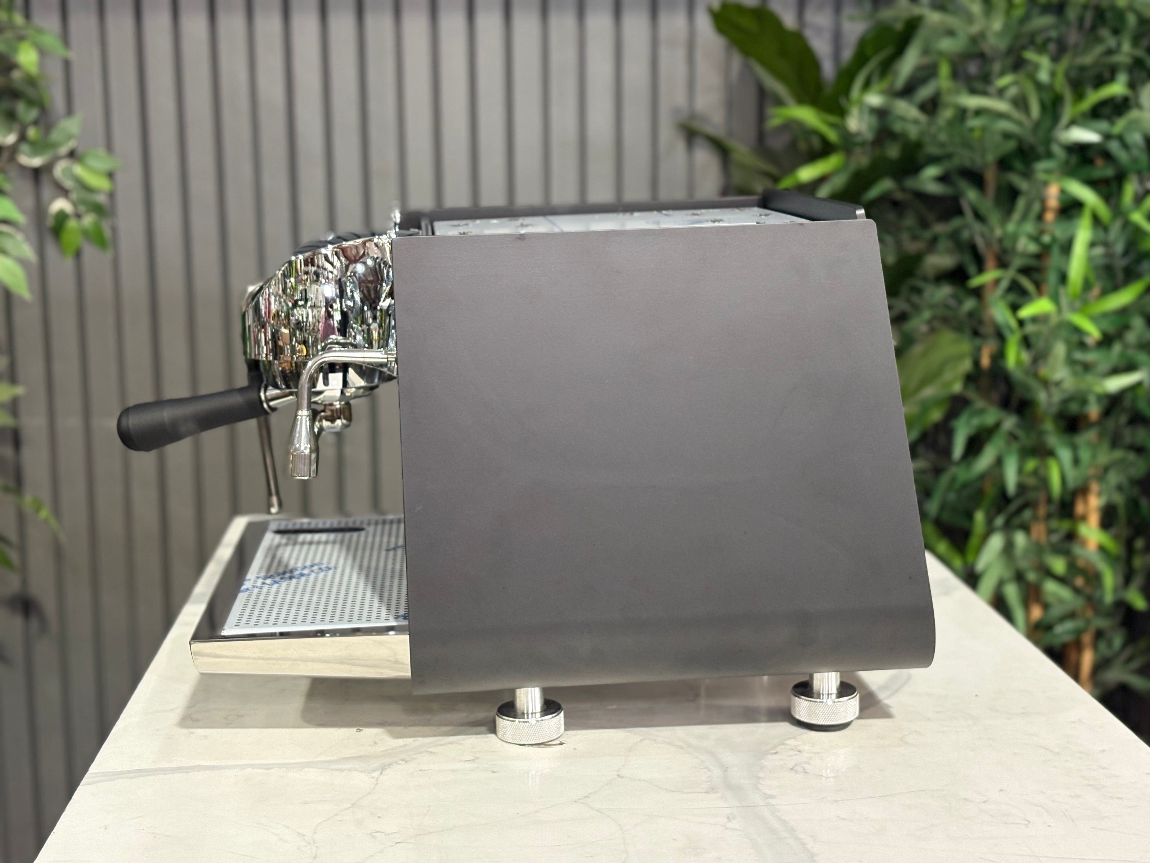 Victoria Arduino Eagle One Prima 1 Group Coffee Machine Black side view on a light countertop with greenery in the background.