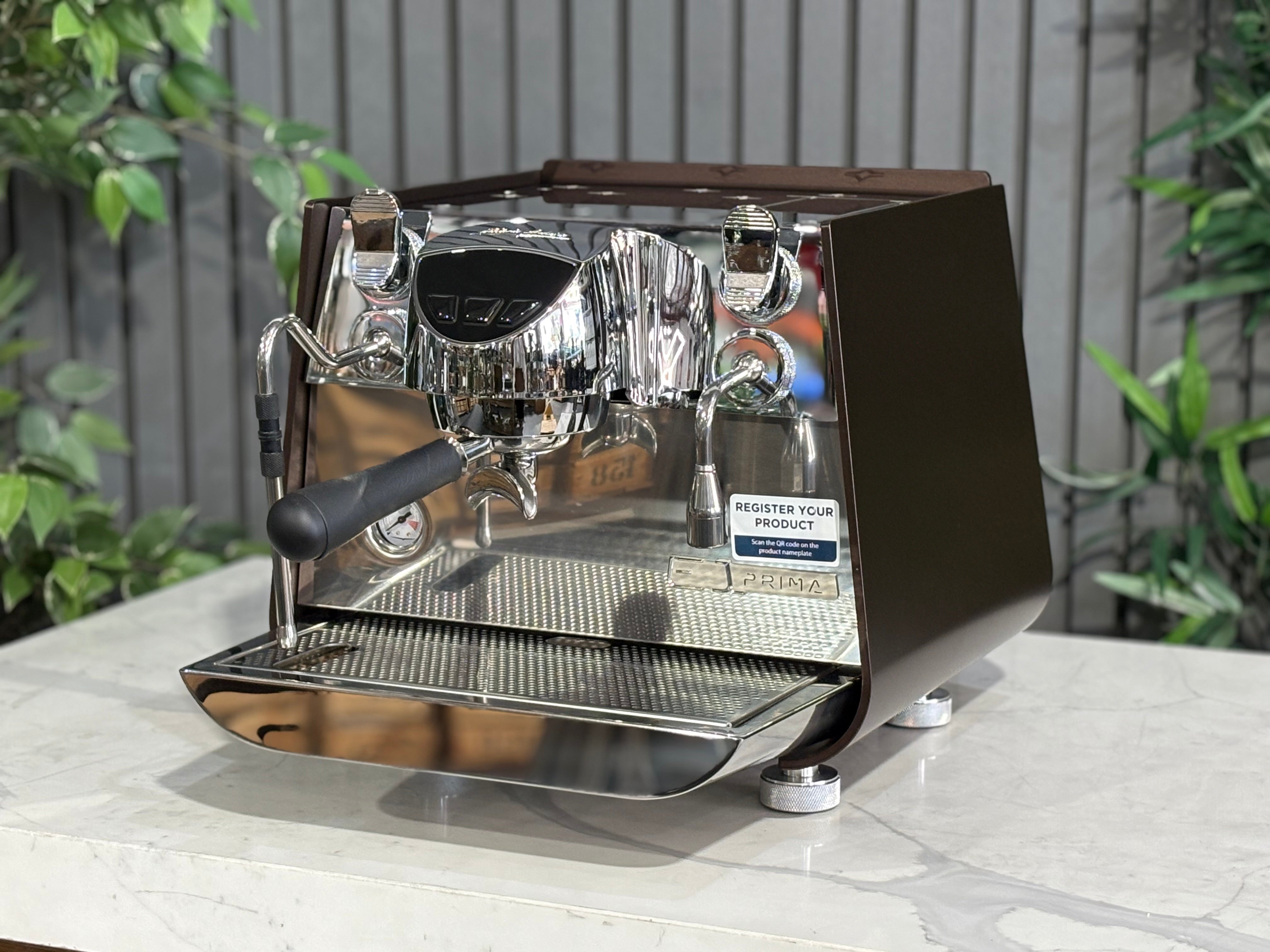 Victoria Arduino Eagle One Prima 1 Group Espresso Machine on a table with foliage in the background.