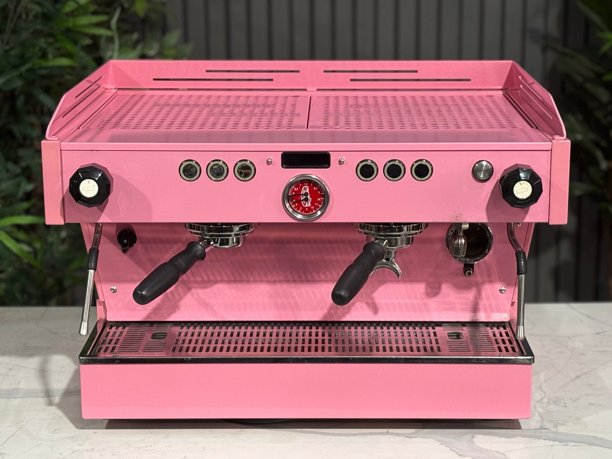 La Marzocco Linea PB 2 Group Coffee Machine Dark Pink top-down front view showing the cup tray, control panel, and clean lines of the espresso machine’s body, sitting on a marble bench with greenery behind.