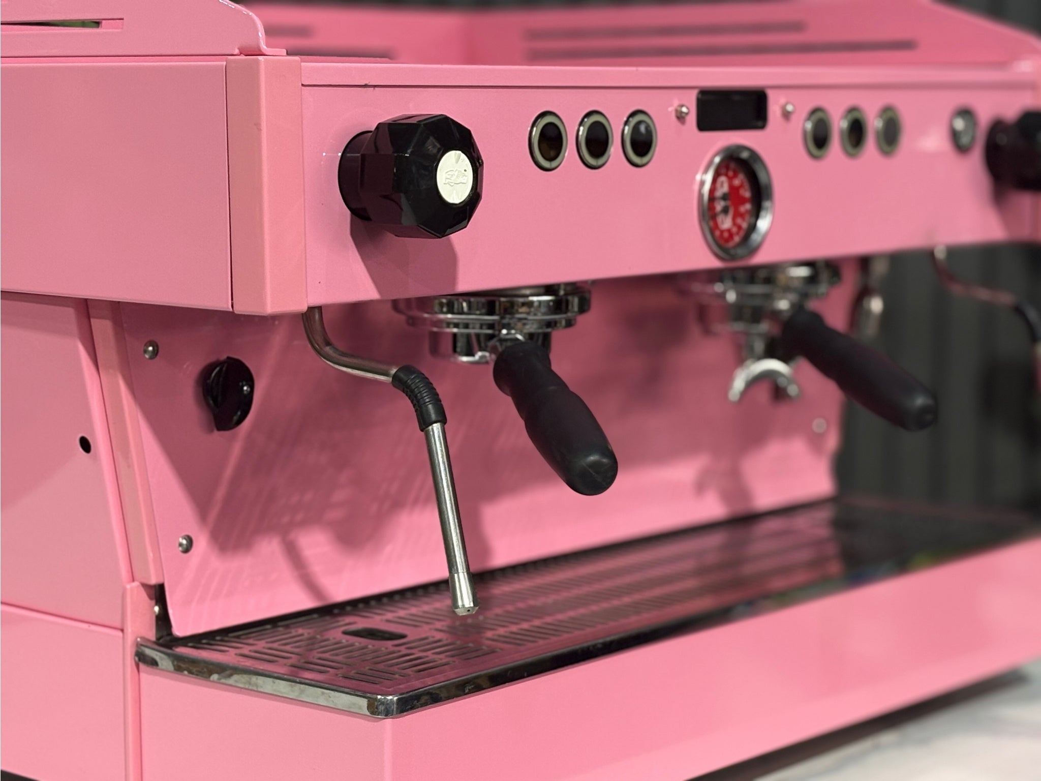 La Marzocco Linea PB 2 Group Coffee Machine Dark Pink front close-up displaying the group head, cup tray, and digital interface, with the machine’s eye-catching espresso features framed by a marble bench and lush green background.