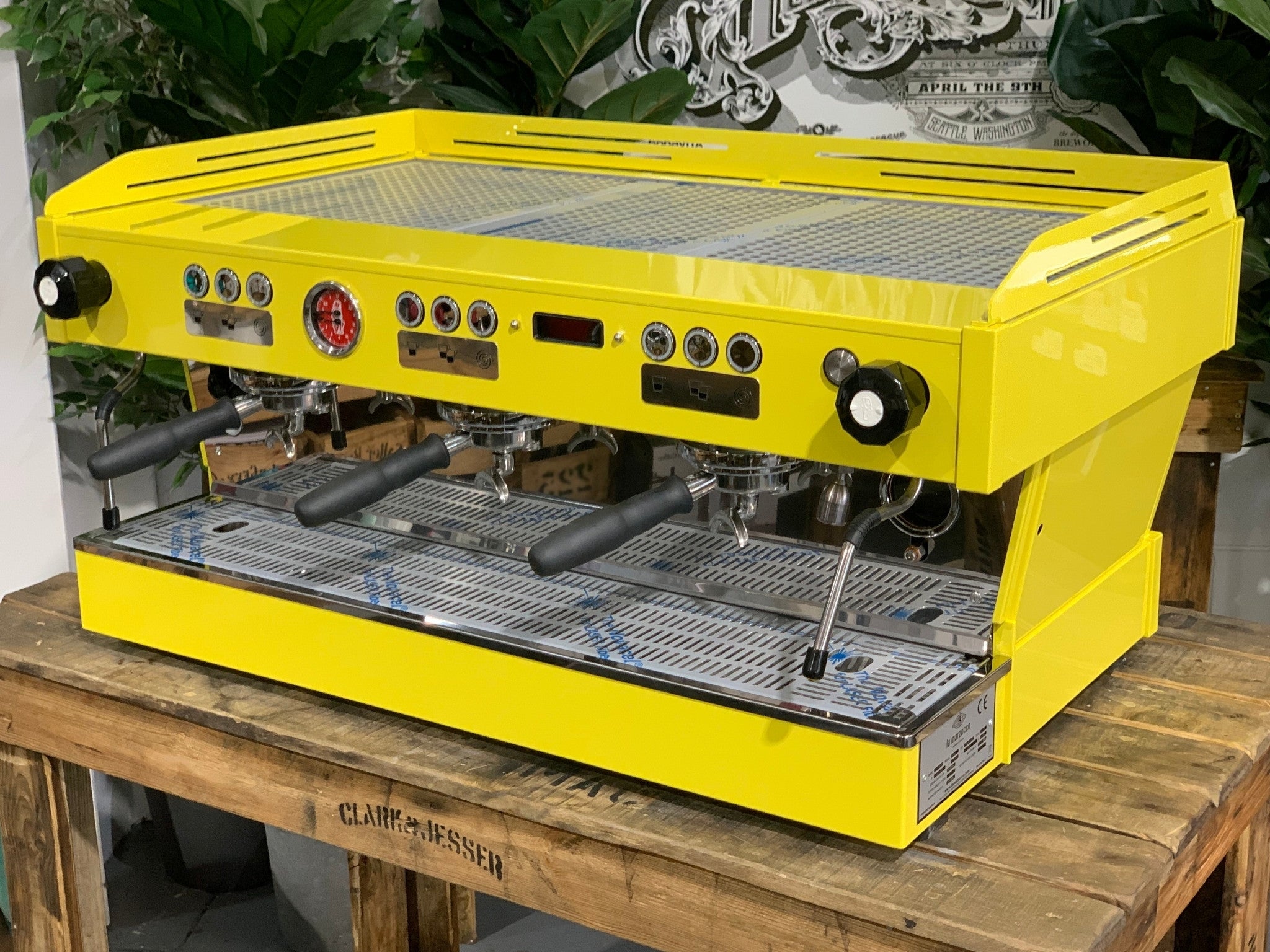 La Marzocco Linea PB 3 Group Coffee Machine Yellow – New espresso coffee machine angled view on a wooden bench with greenery, showing group heads, dual steam wands, cup tray, and LED display.