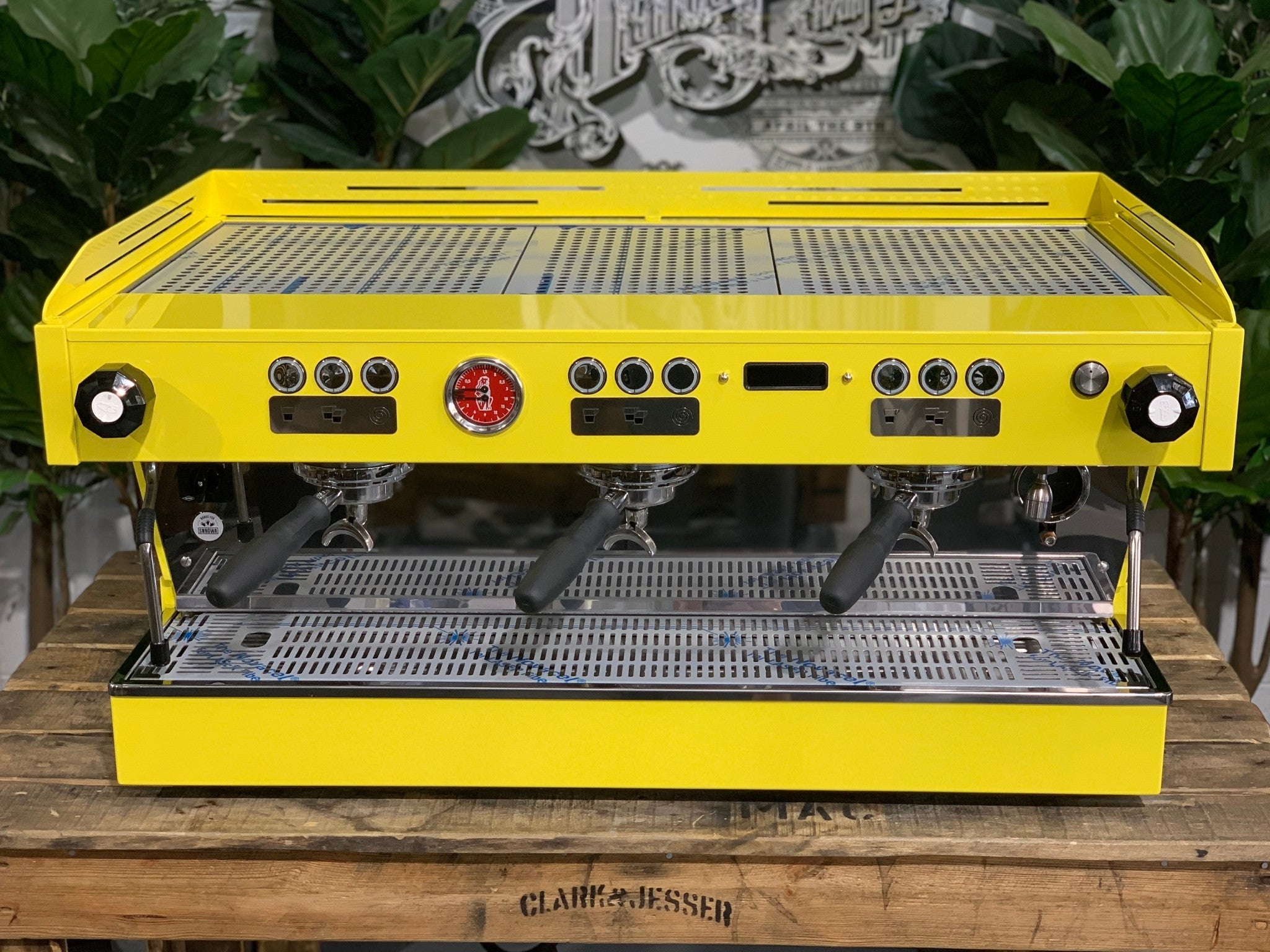 La Marzocco Linea PB 3 Group Coffee Machine Yellow – New front view espresso machine on wooden bench with greenery, featuring three group heads, dual steam wands, cup tray, and digital display.