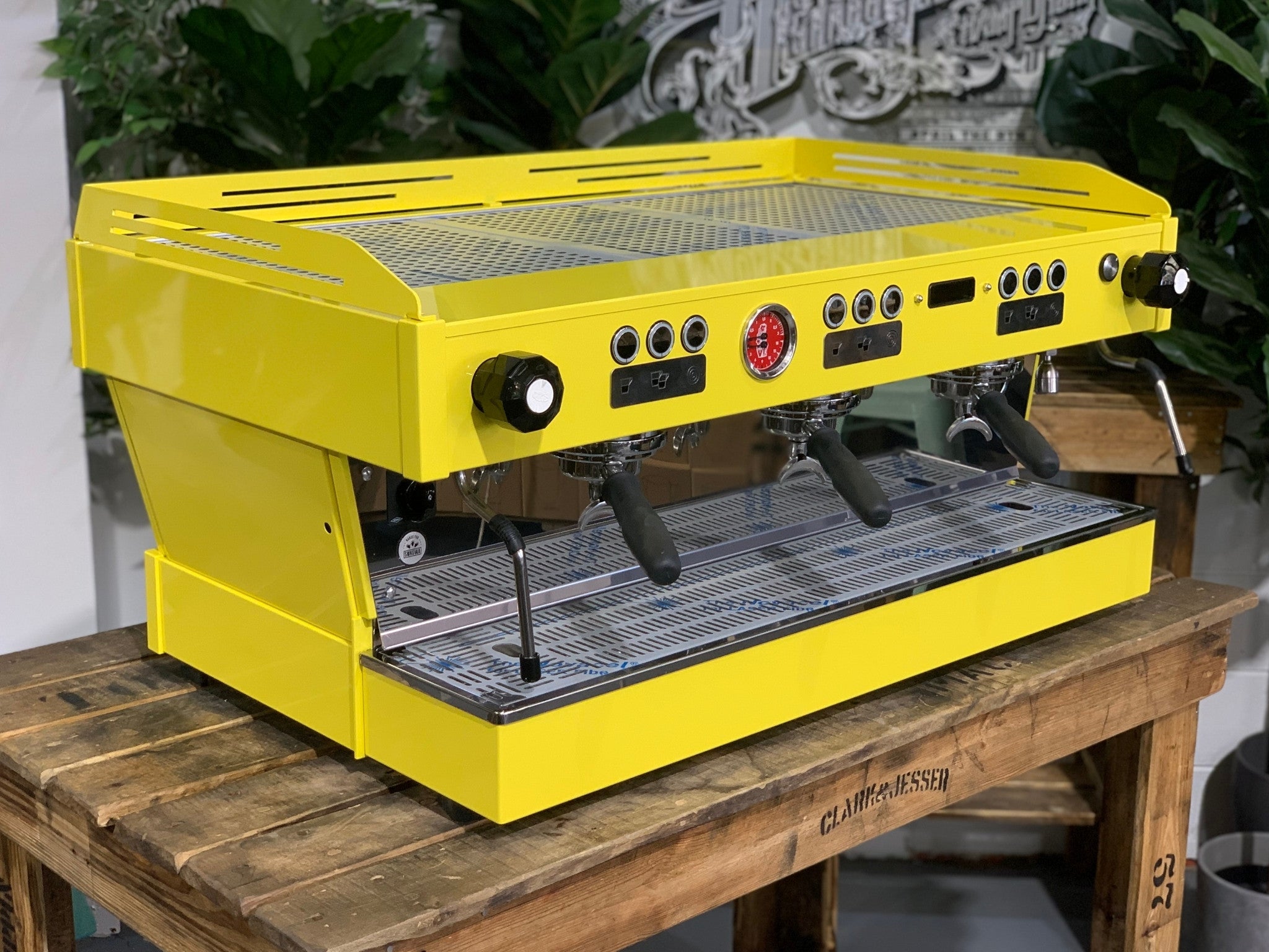 La Marzocco Linea PB 3 Group Coffee Machine Yellow – New espresso coffee machine angled view on a wooden bench with greenery, showing group heads, dual steam wands, cup tray, and LED display.