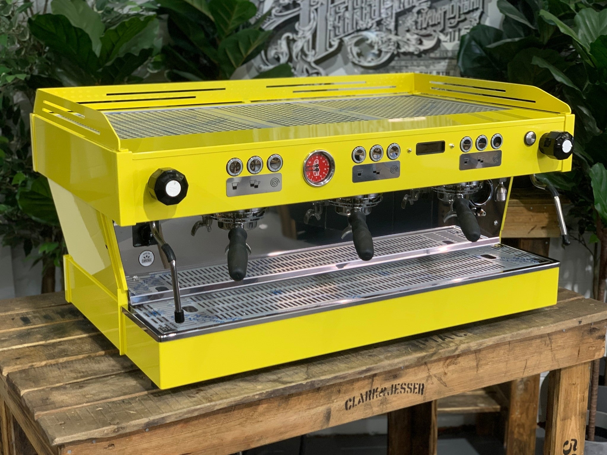 La Marzocco Linea PB 3 Group Coffee Machine Yellow – New espresso coffee machine angled view on a wooden bench with greenery, showing group heads, dual steam wands, cup tray, and LED display.