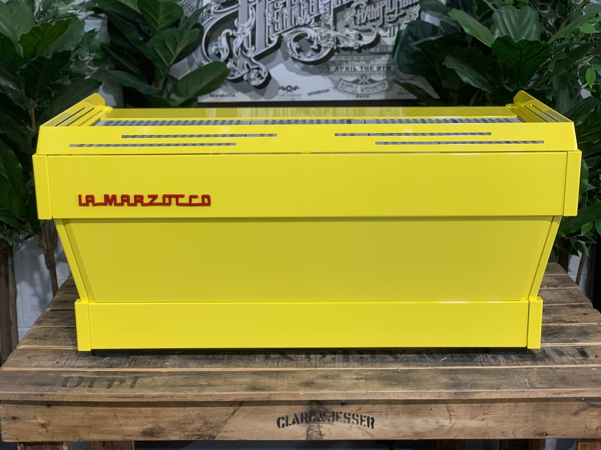 La Marzocco Linea PB 3 Group Coffee Machine Yellow – New espresso coffee machine rear view on wooden bench with greenery, showing yellow stainless steel body and clean back panel design.