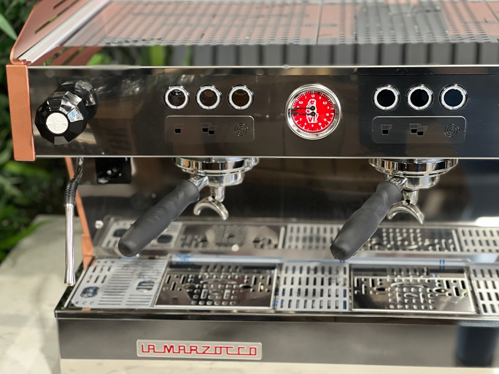 La Marzocco Linea PB ABR 3 Group Coffee Machine White & Copper - New close-up front view of the three saturated group heads resting on the ABR drip tray with integrated scales, with copper accents and part of the digital LED display visible, on a marble bench with greenery.