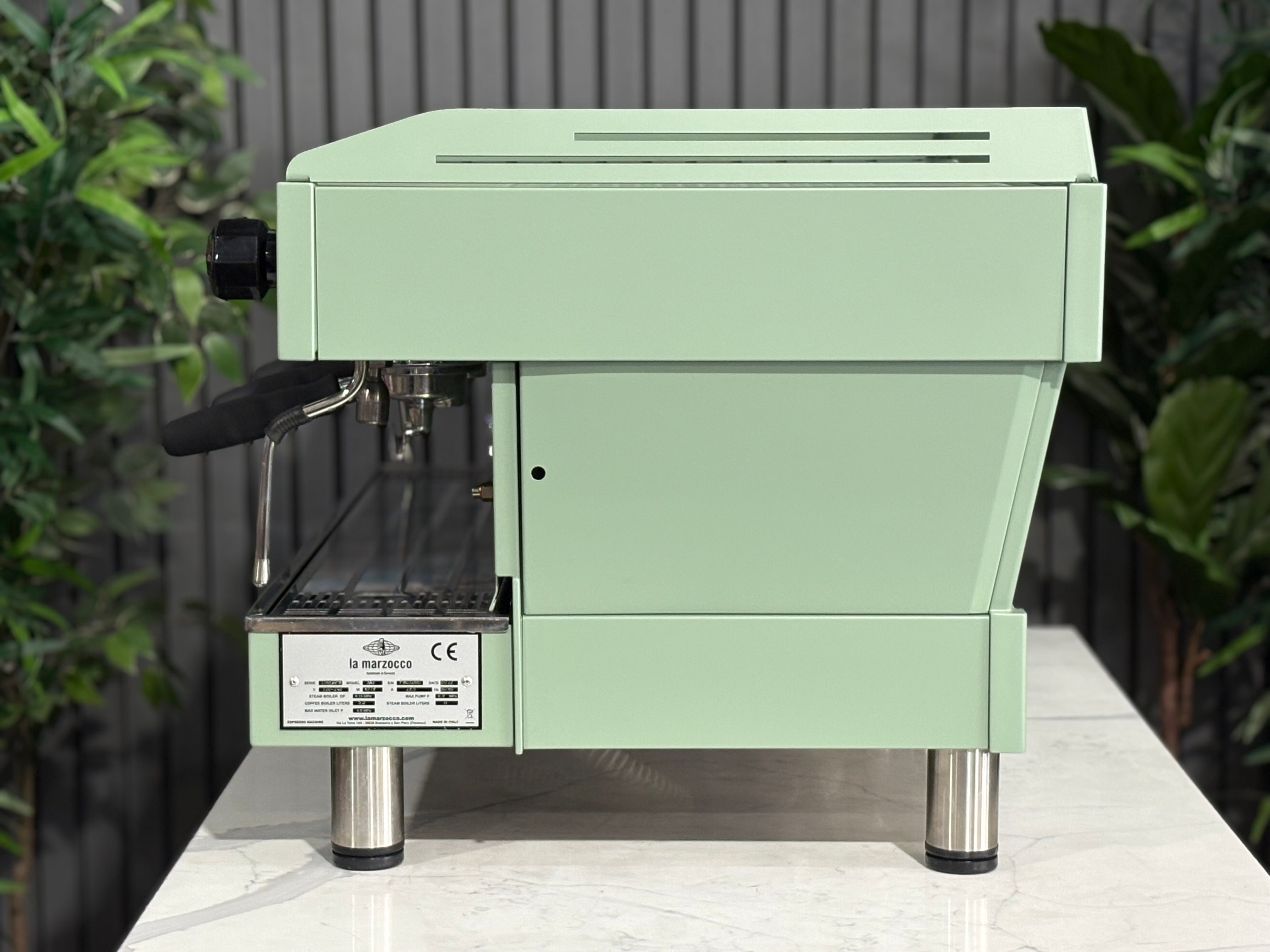 La Marzocco Linea PB 3 Group Coffee Machine Mint Green - Used side view on countertop with plants in background.