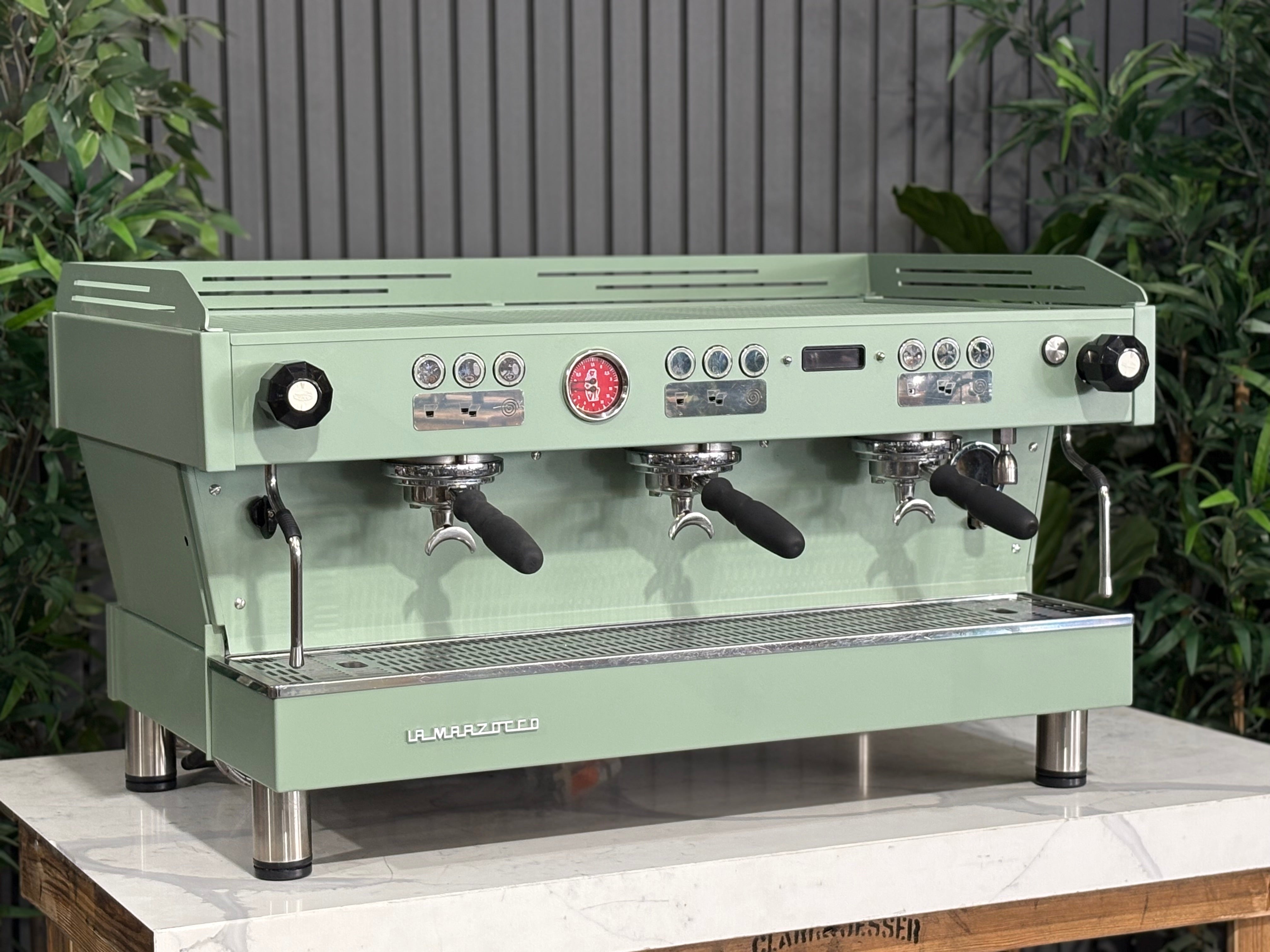 La Marzocco Linea PB 3 Group Coffee Machine Mint Green - Used displayed in a café setting with lush greenery in the background.