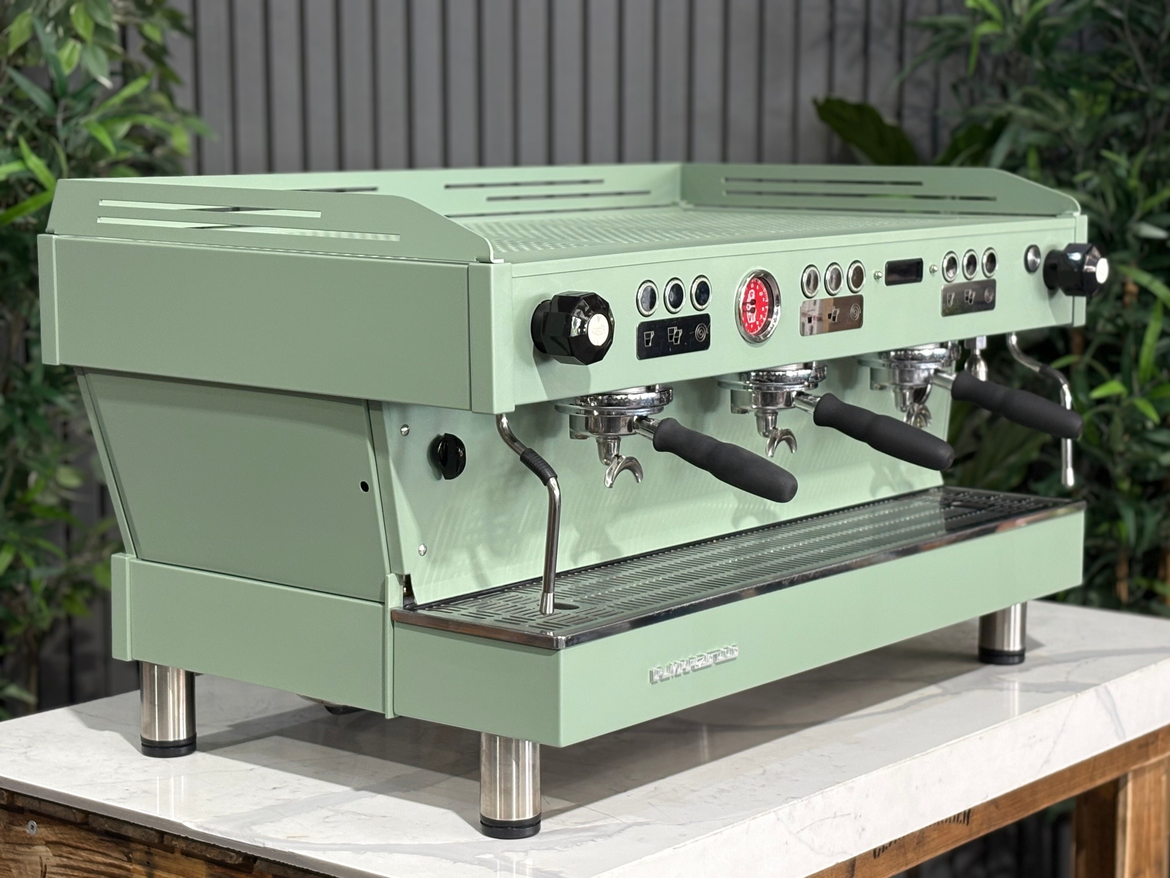 La Marzocco Linea PB 3 Group Coffee Machine Mint Green - Used displayed on a counter surrounded by greenery.