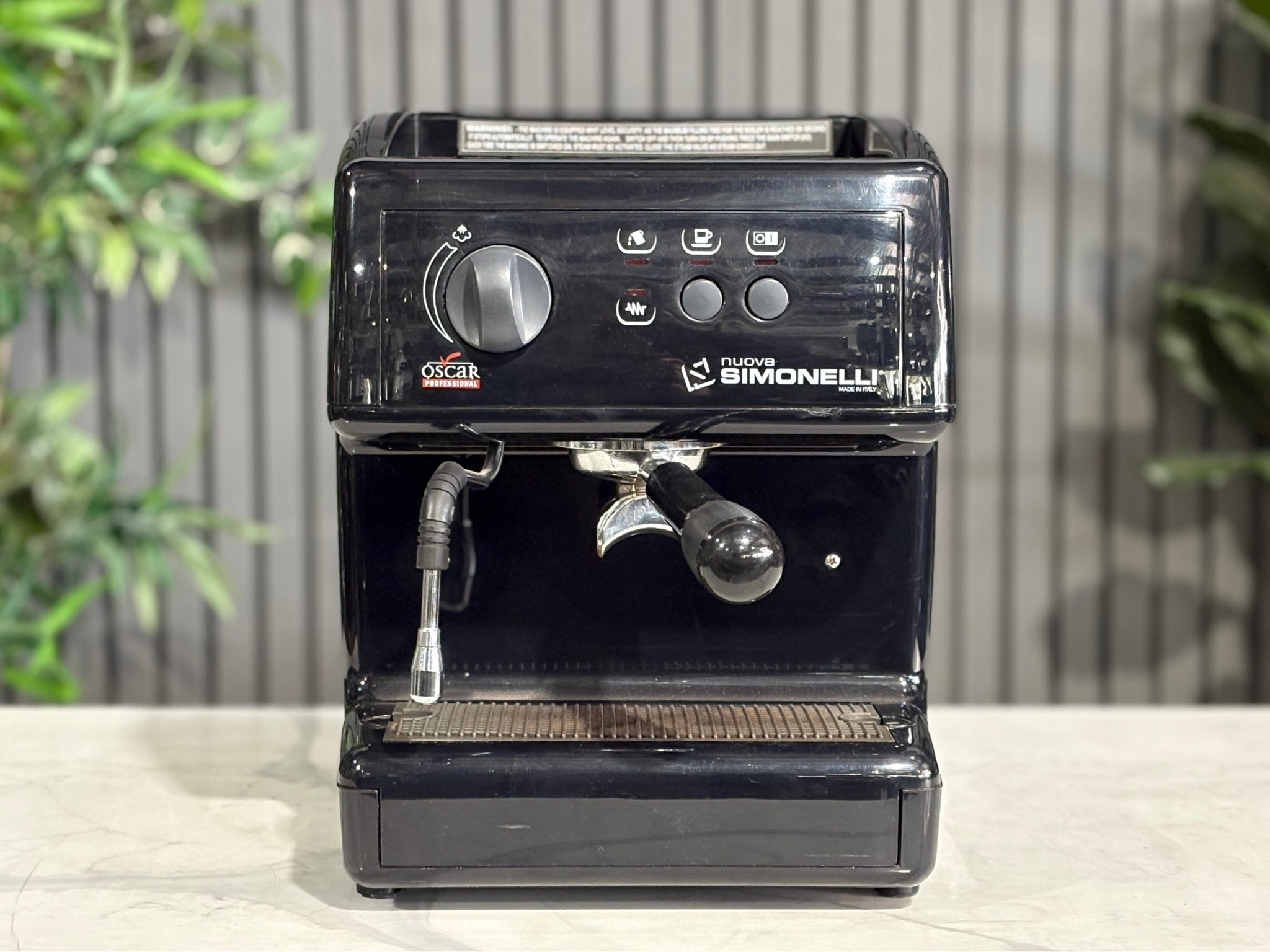 Nuova Simonelli Oscar Professional 1 Group Coffee Machine Black - Used espresso coffee machine shown front-on, clearly highlighting the group head, control buttons, and compact frame. Positioned on a marble bench with greenery in the background.