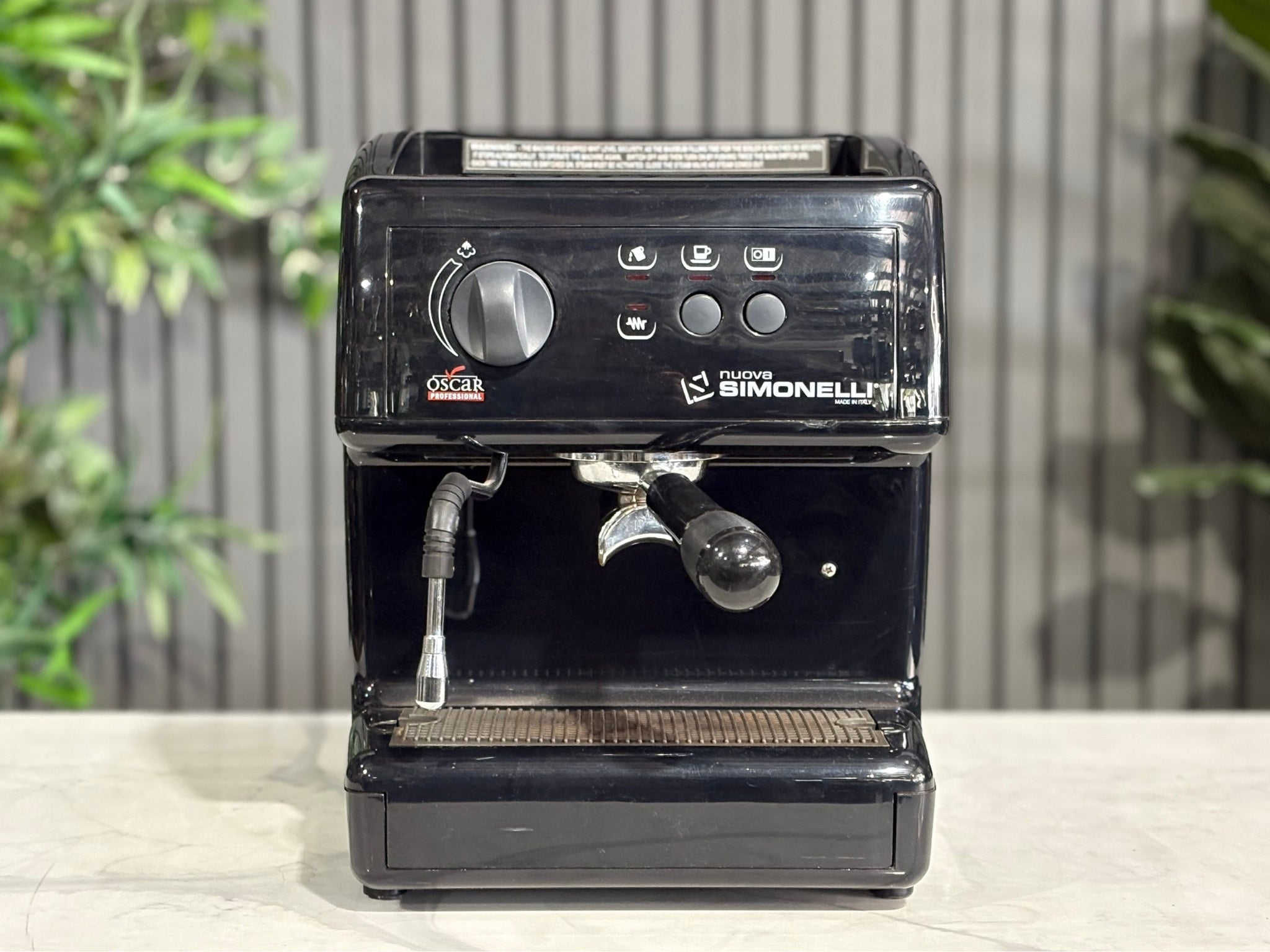 Nuova Simonelli Oscar Professional 1 Group Coffee Machine Black - Used espresso coffee machine shown front-on, clearly highlighting the group head, control buttons, and compact frame. Positioned on a marble bench with greenery in the background.