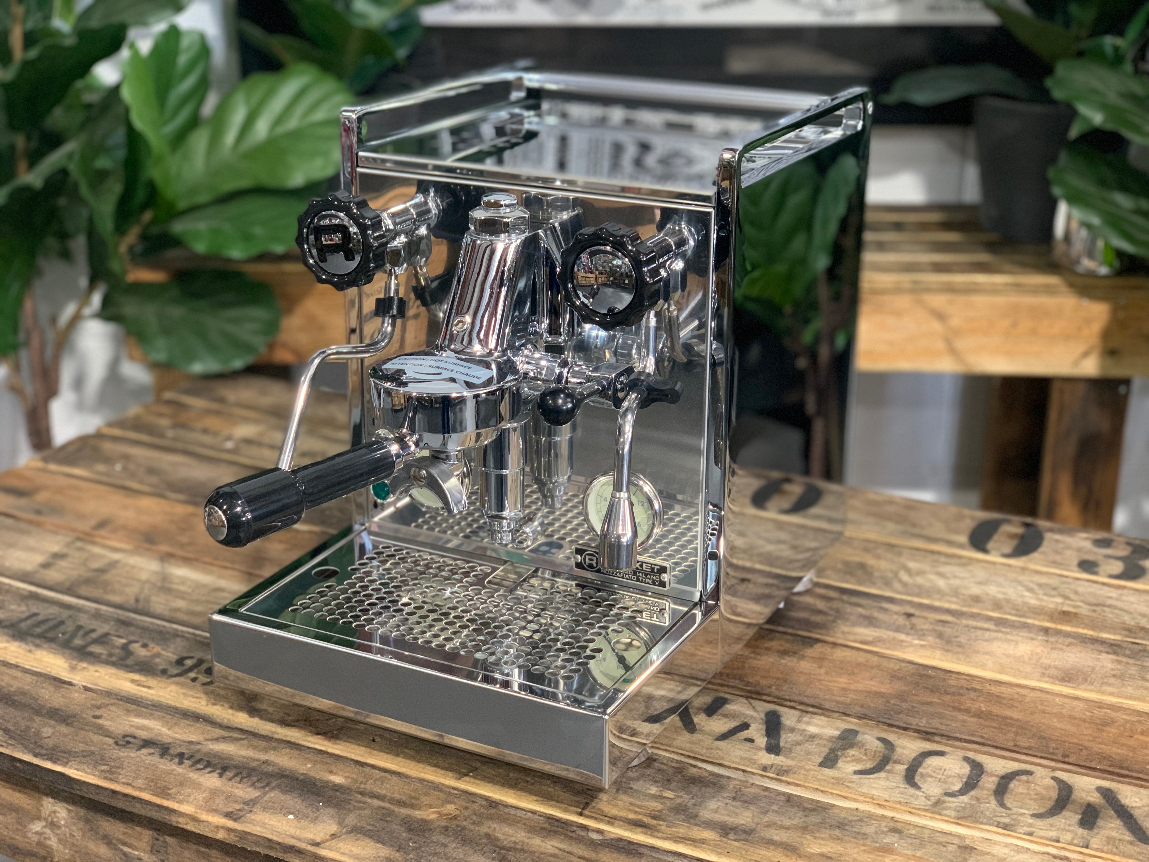 Rocket Mozzafiato Cronometro V 1 Group Coffee Machine - New on wooden counter with plants in background.