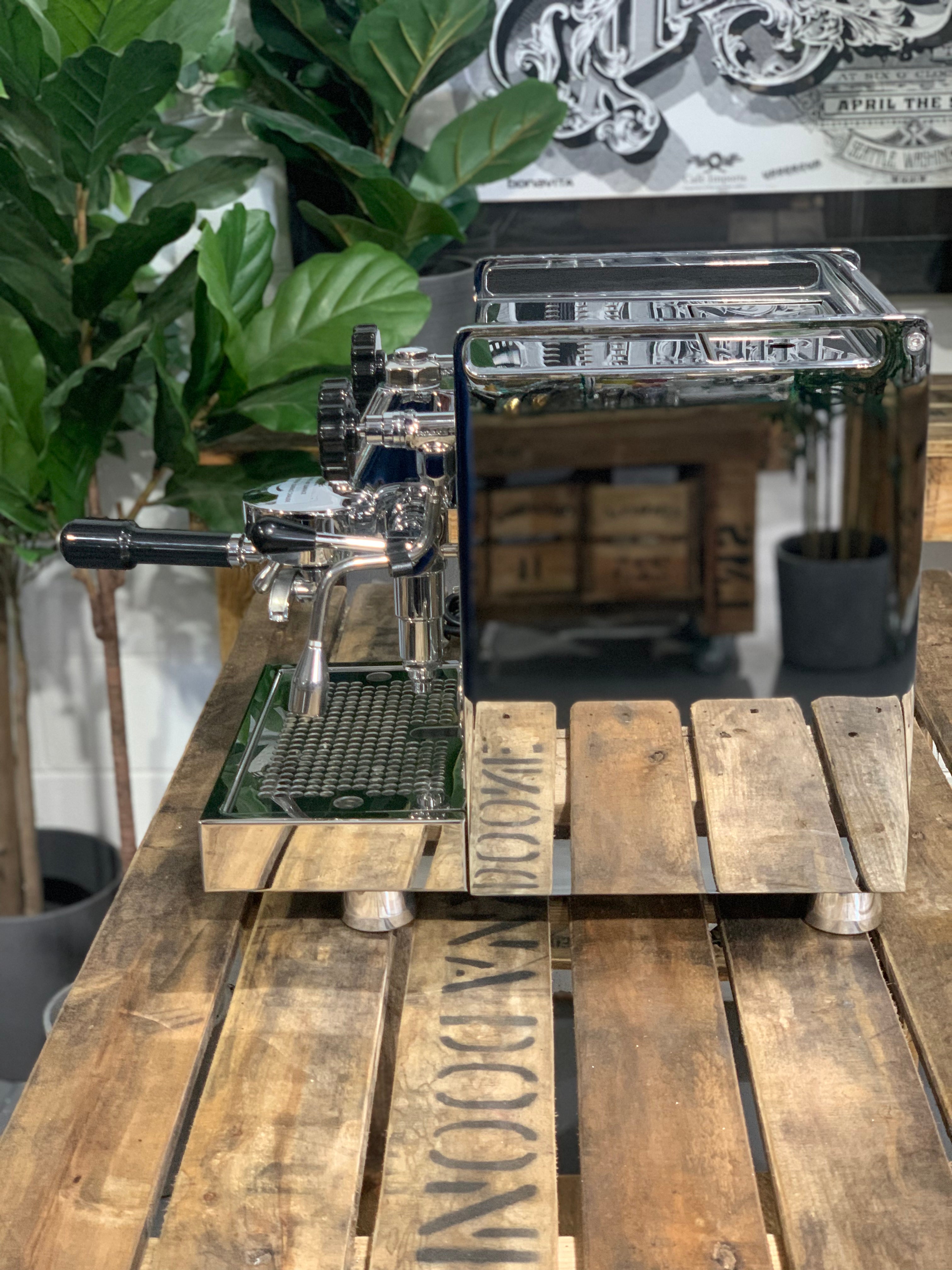 Rocket Mozzafiato Cronometro V 1 Group Coffee Machine - New on a wooden table with plants in background.