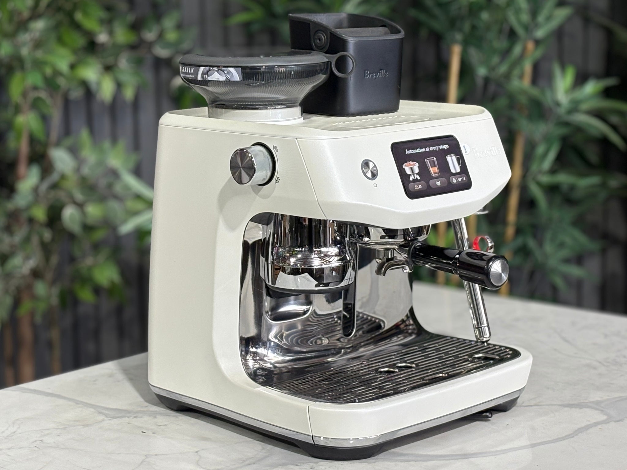 Breville Oracle Jet 1 Group Coffee Machine White - New, angled view on a marble bench with greenery, showing the white body, group head, milk steamer, and 340g hopper.