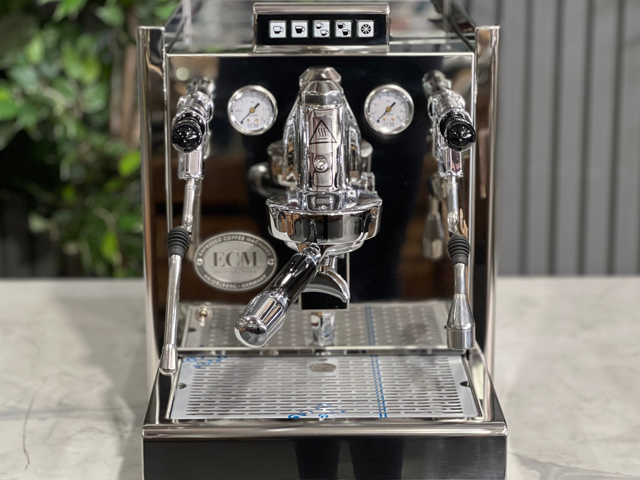 CM Elektronika II Profi Rotary 1 Group Coffee Machine Stainless – New, close-up front view of the E61 group head, PID gauges, steam wand, and cup tray on a marble bench with greenery in the background.