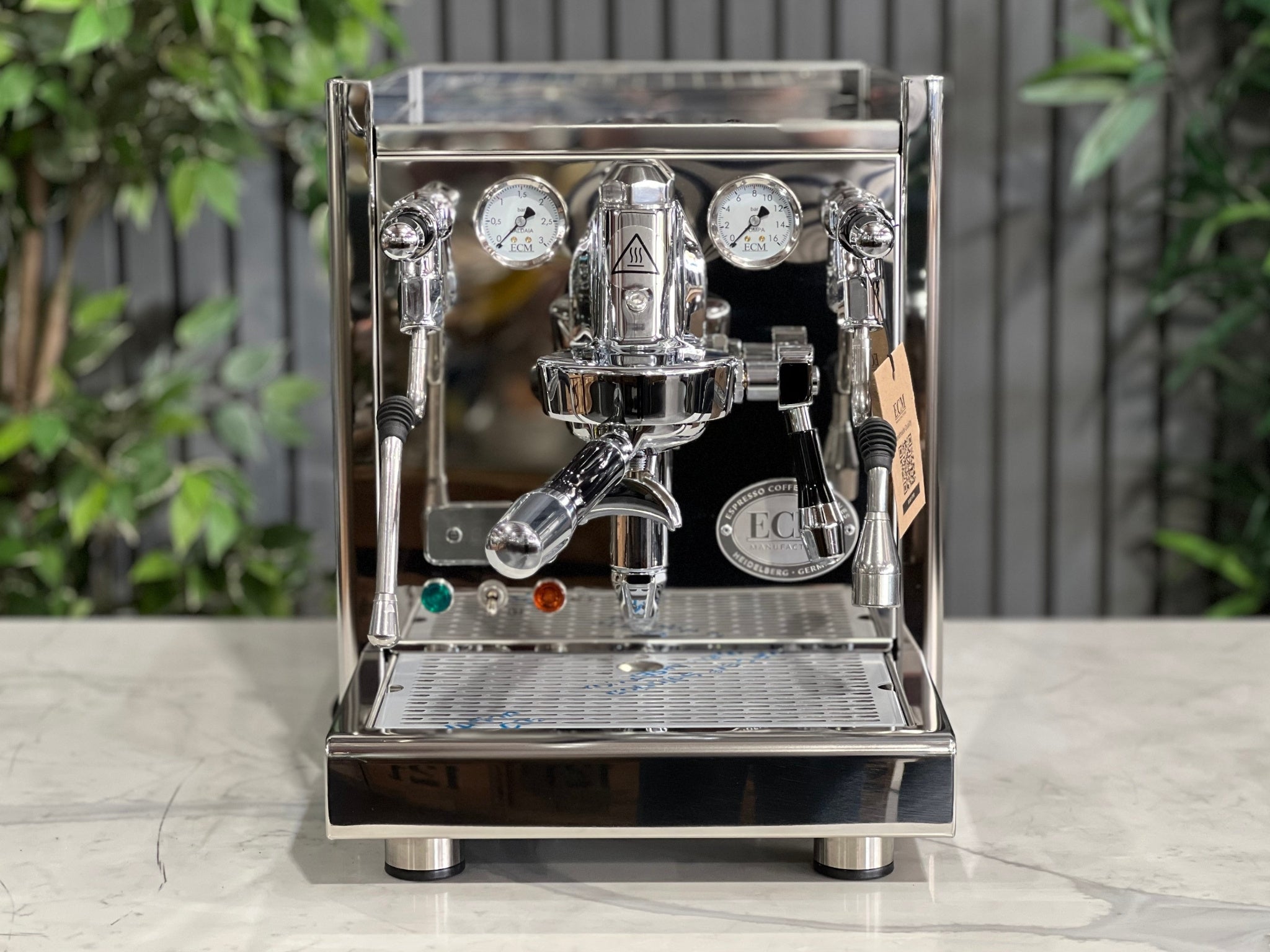 ECM Technika V Profi Rotary PID 1 Group Coffee Machine Stainless – New espresso coffee machine viewed front-on on a marble bench with greenery behind, showing the polished stainless steel body, E61 group head, easy tap levers, and dual pressure gauges