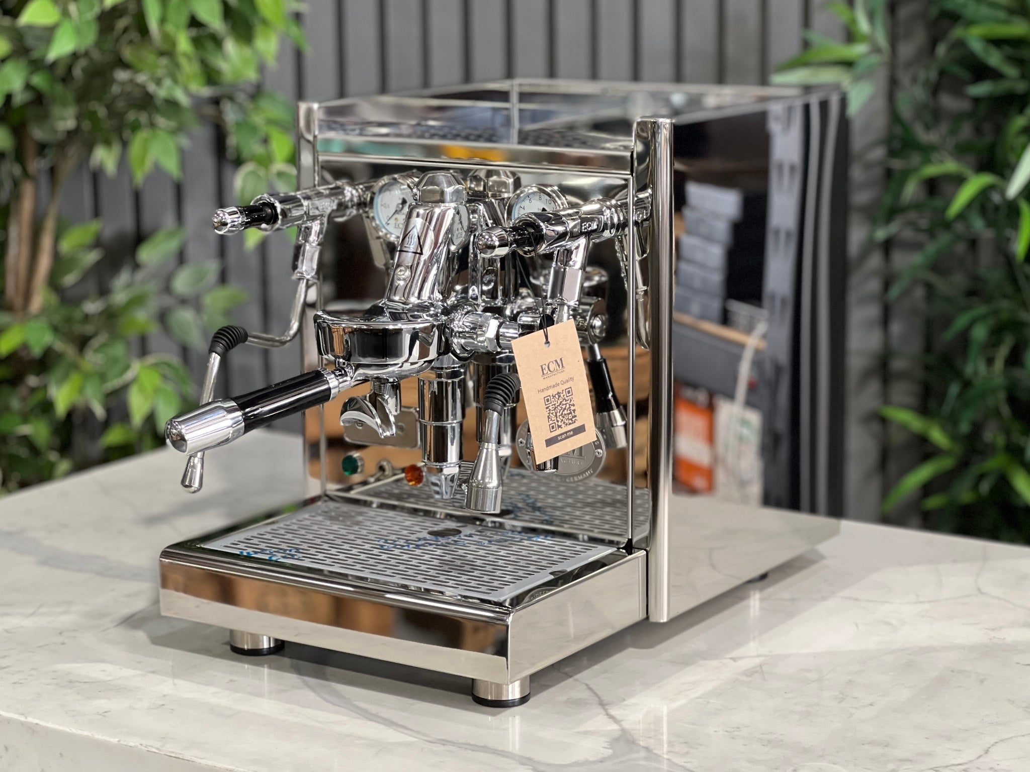 ECM Technika V Profi Rotary PID 1 Group Coffee Machine Stainless – New espresso coffee machine shown at an angled view on a white marble bench with greenery behind, displaying the E61 group head, dual gauges, and stainless steam wand.