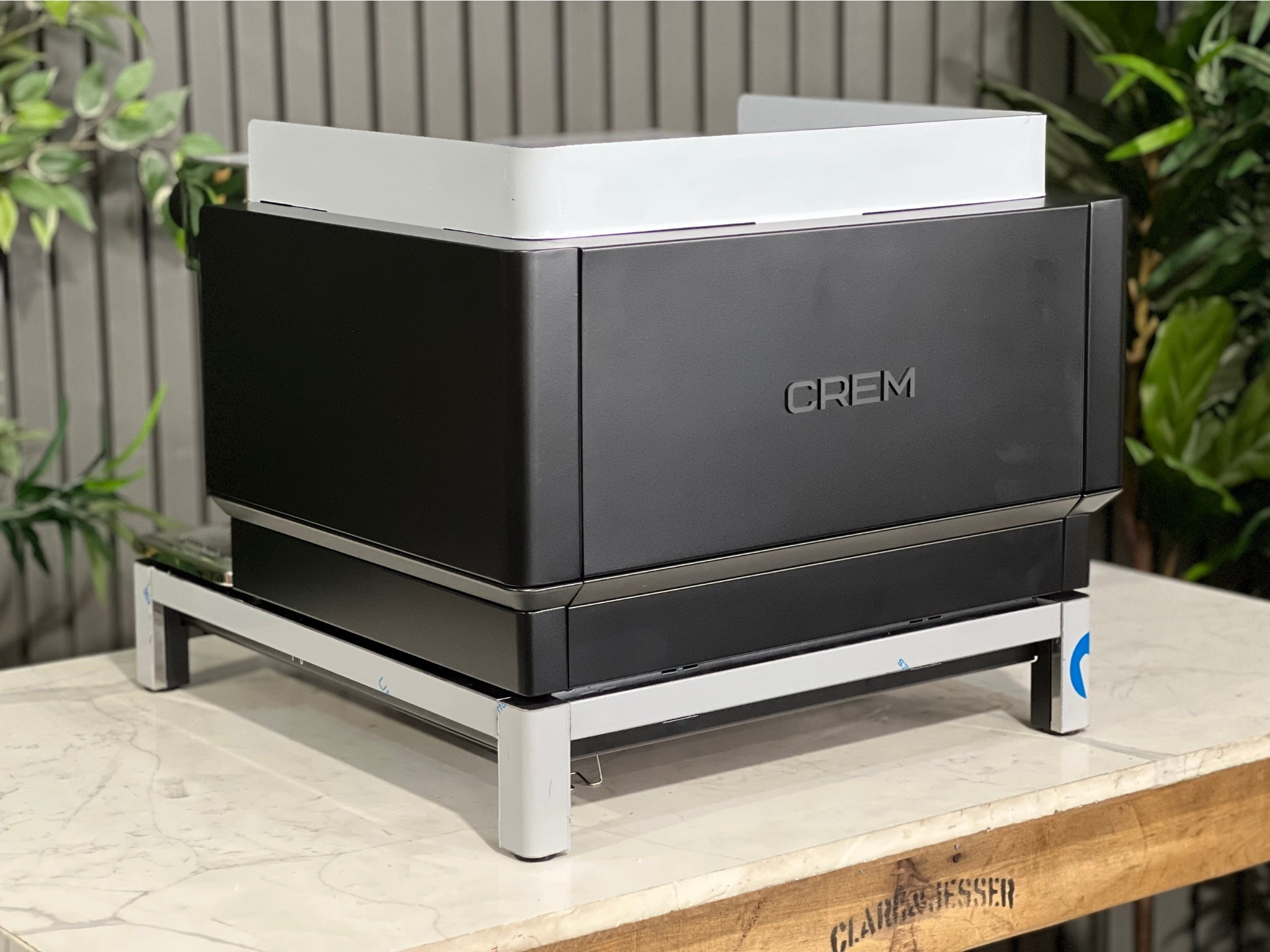 Expobar Crem EX3 Compact 1 Group Coffee Machine Black - New angled rear image showing the curvature of the frame and the compact footprint of the espresso machine. The black finish contrasts beautifully with the marble bench and green background.
