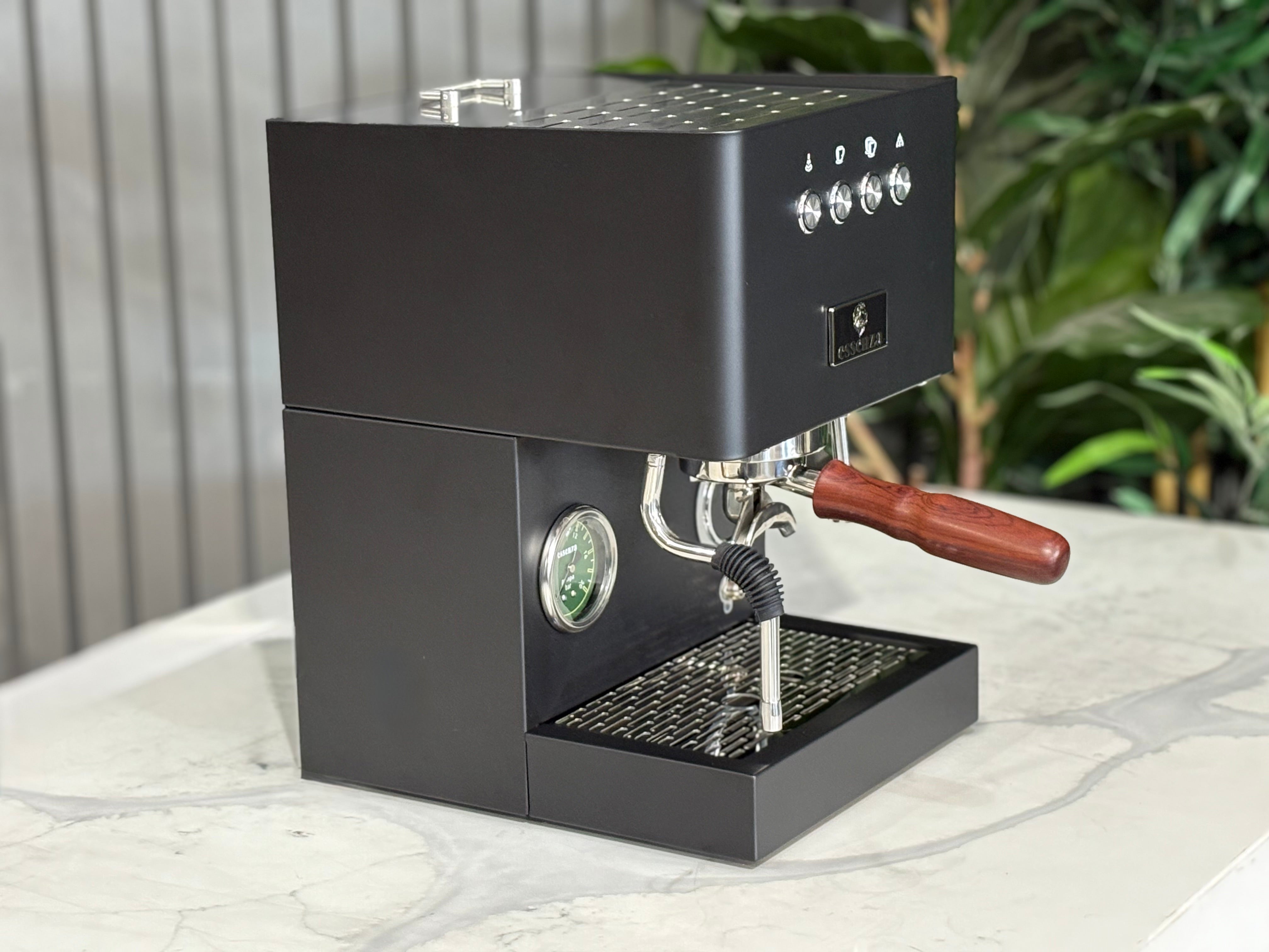 Essenza Nina 1 Group Coffee Machine Stainless displayed on a marble countertop with greenery in the background.