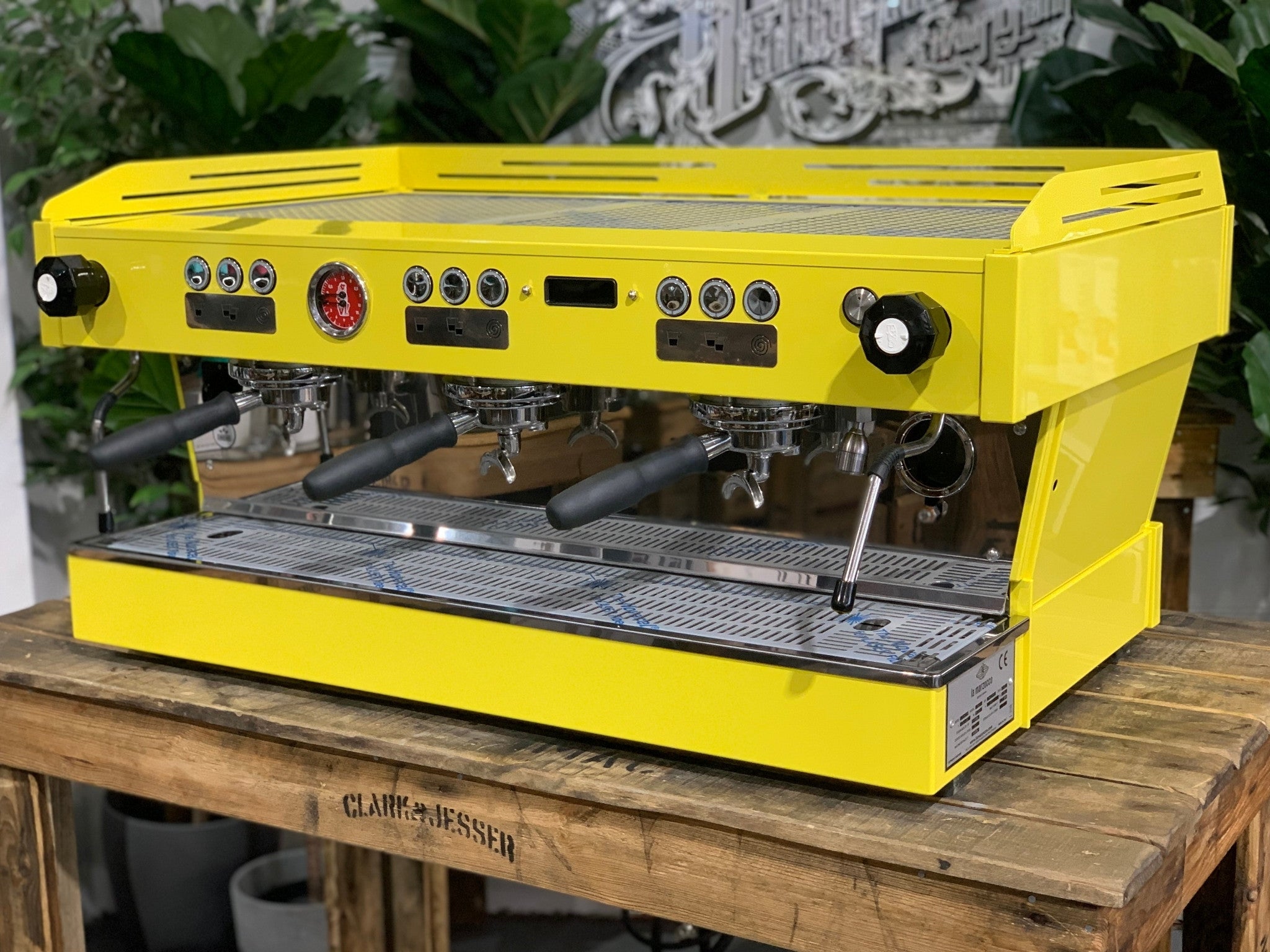 La Marzocco Linea PB 3 Group Coffee Machine Yellow – New espresso coffee machine angled view on a wooden bench with greenery, showing group heads, dual steam wands, cup tray, and LED display.