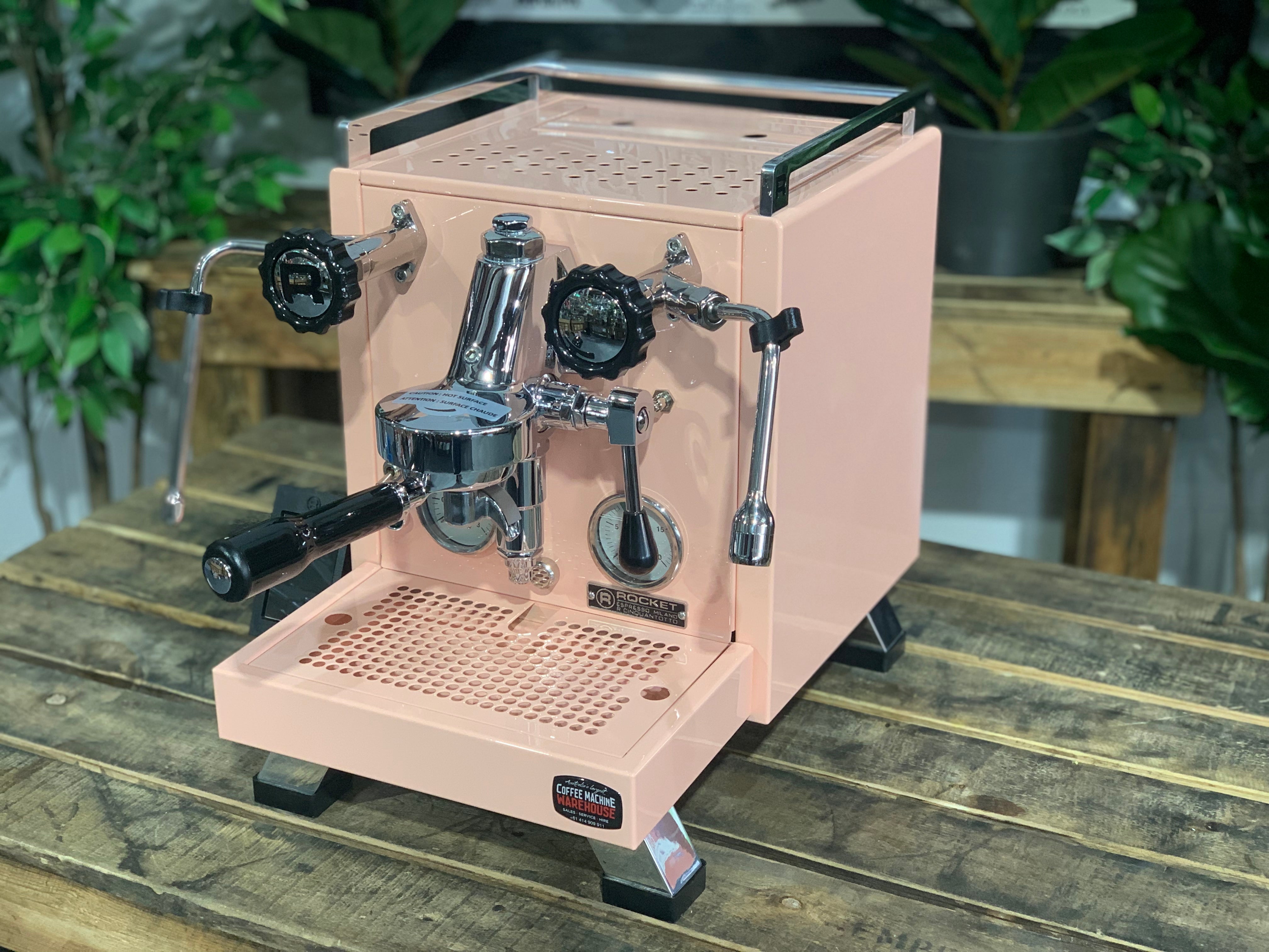 Rocket Cinquantotto R58 1 Group Coffee Machine Pink - New displayed on a wooden table with lush greenery in the background.