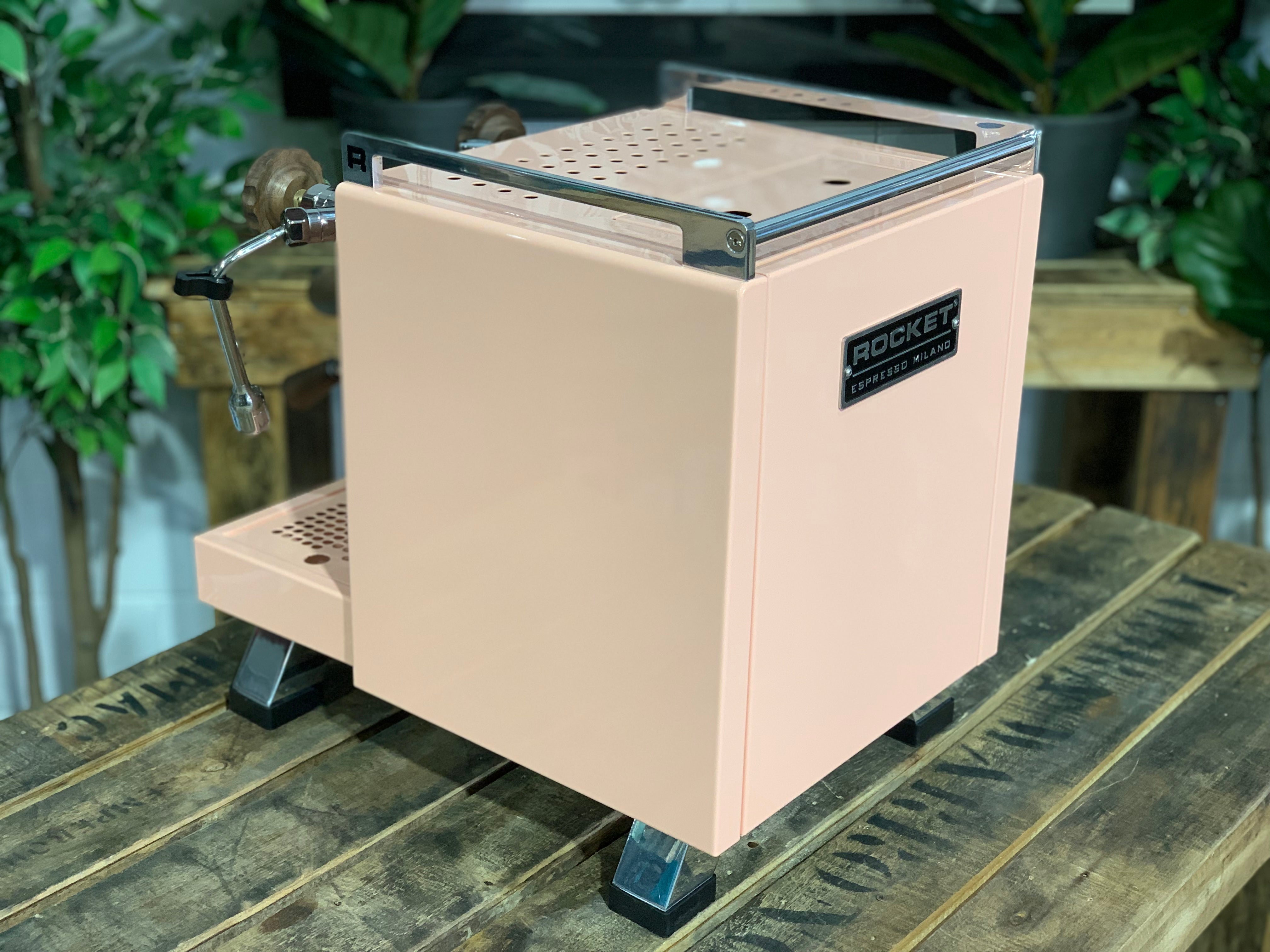 Rocket Cinquantotto R58 1 Group Coffee Machine - New in pink finish on wooden surface with plants in background.