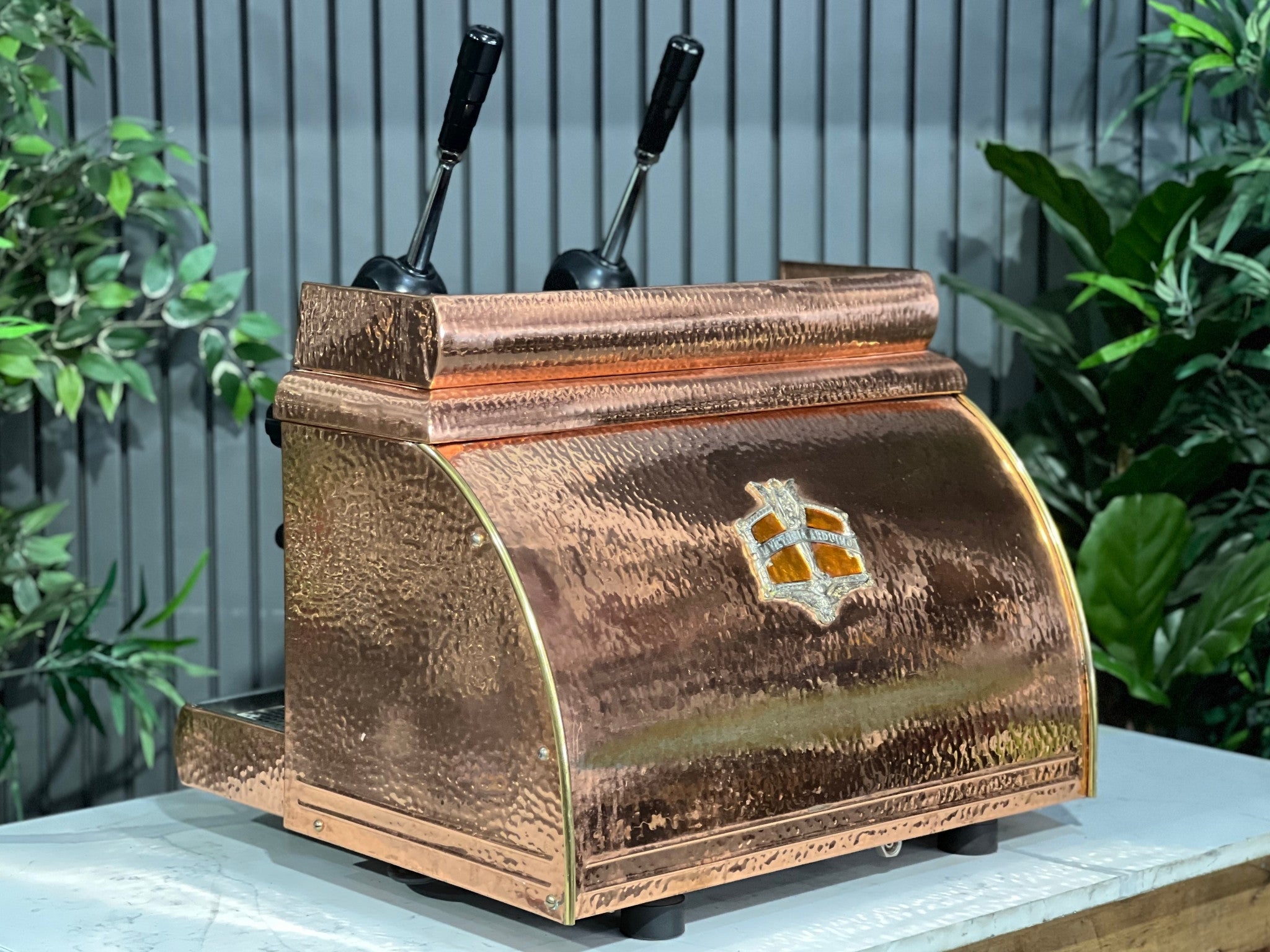 Victoria Arduino Athena Leva 2 Group Coffee Machine Bronze – Used espresso coffee machine shown from an angled back view, revealing the bronze rear panel, lever system, and polished side detailing on a marble bench.